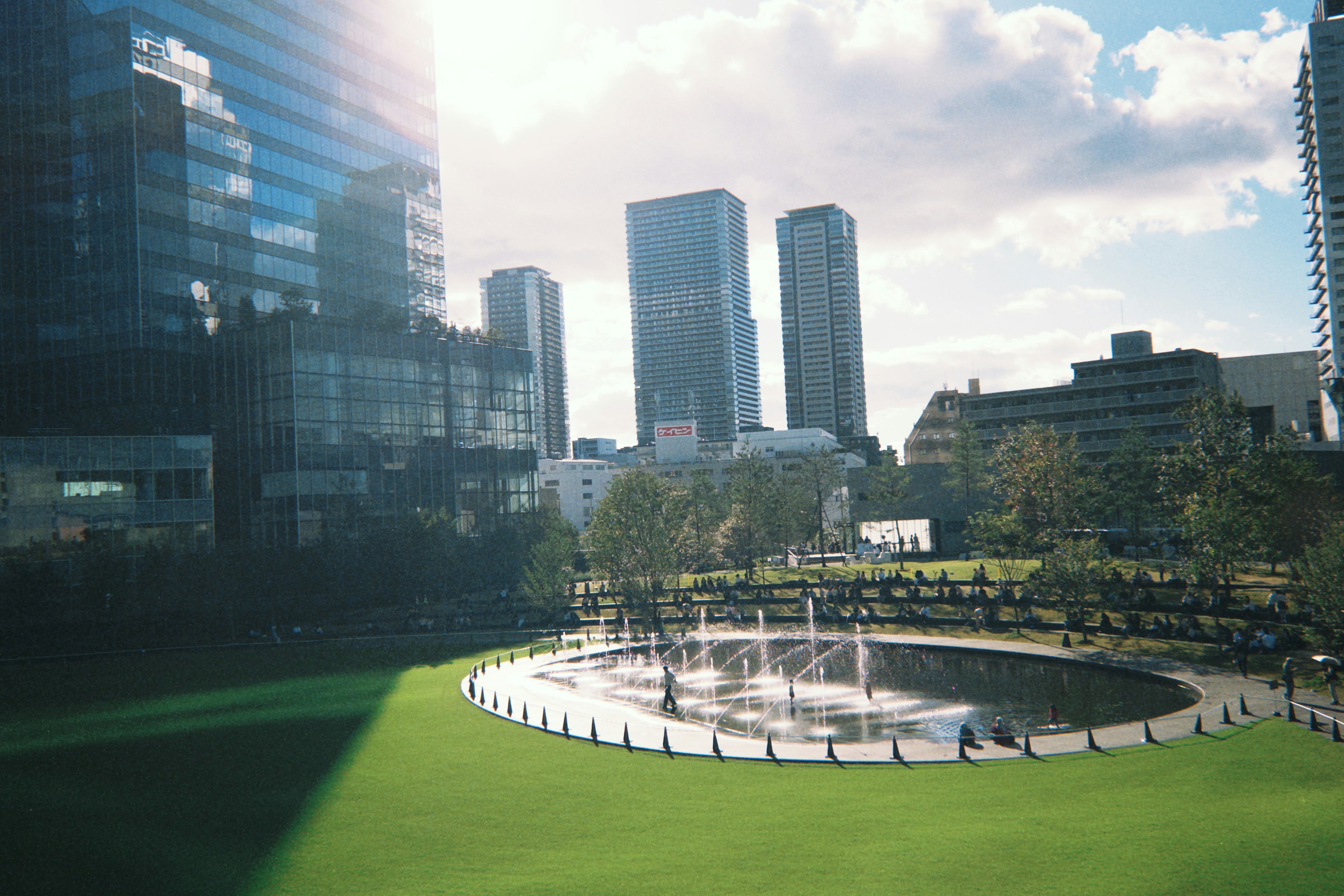 Vista de un parque verde con rascacielos modernos luz del sol