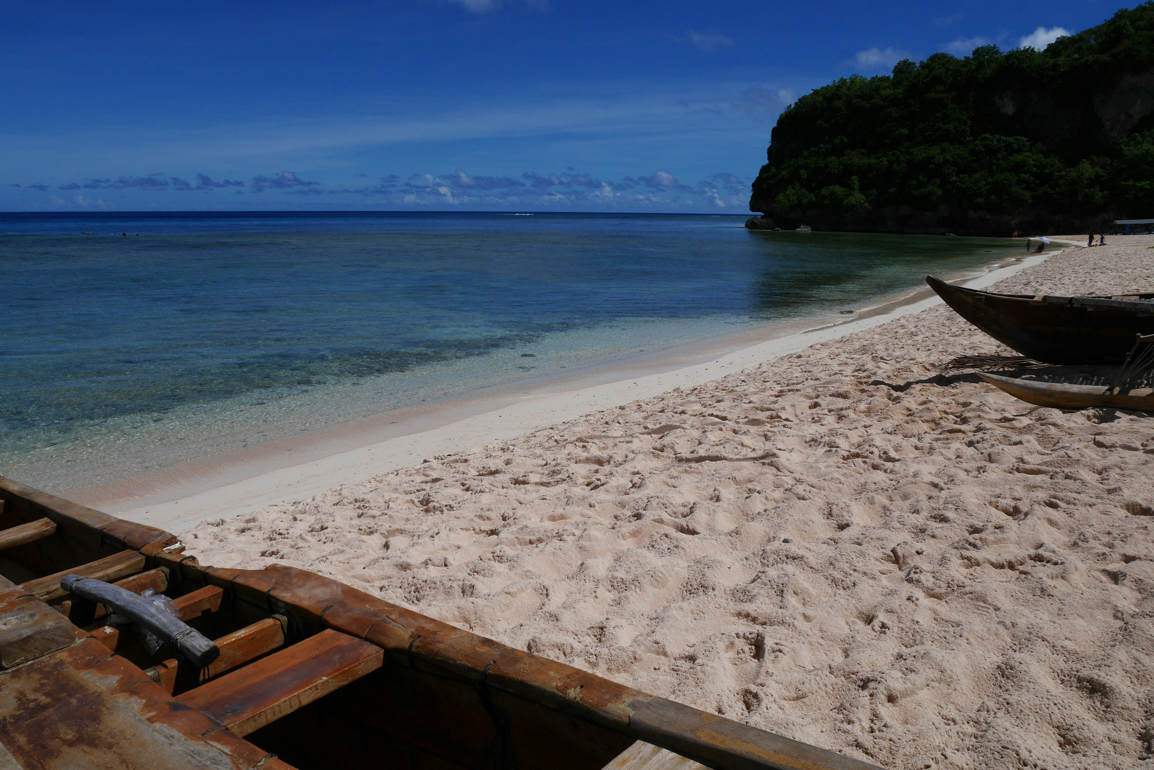 Vue de plage pittoresque avec eau claire et rivage de sable présentant un bateau en bois