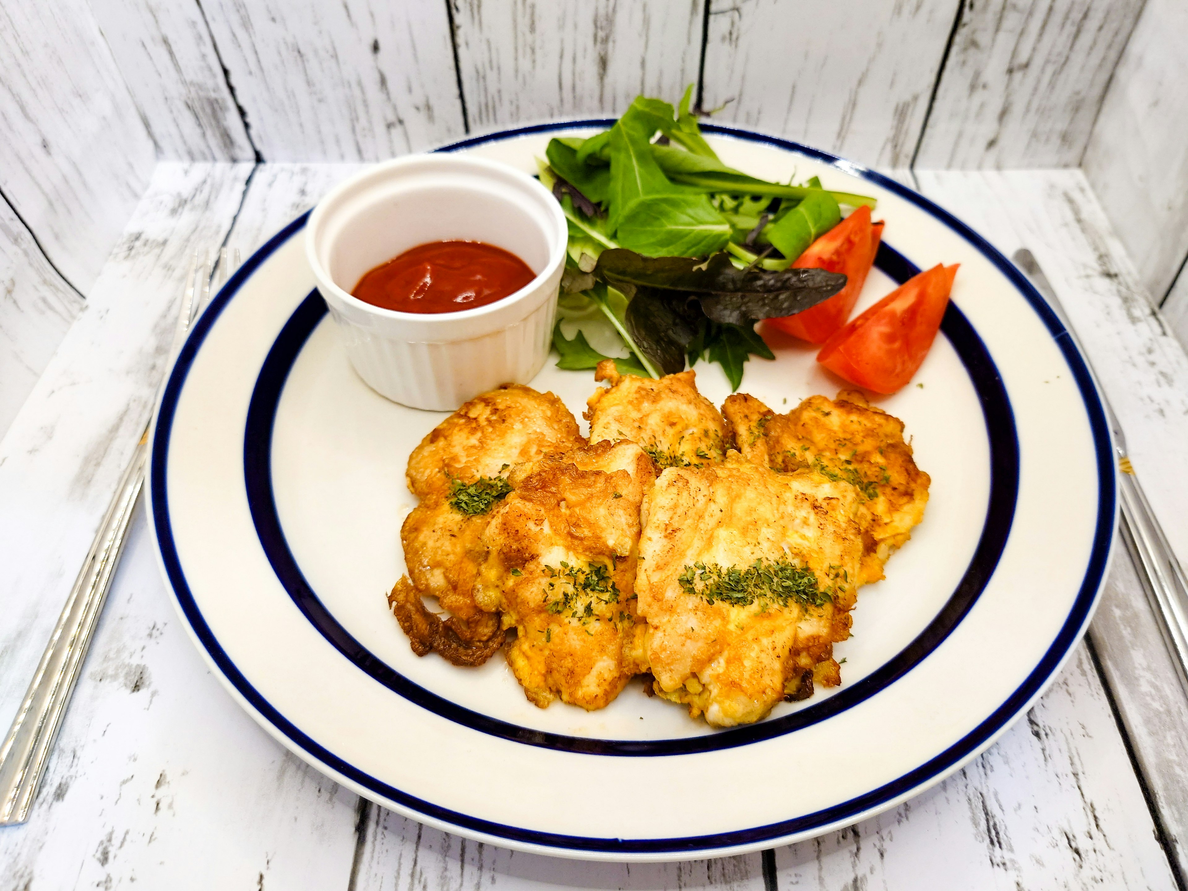 Fried fish dish served with salad and tomato slices