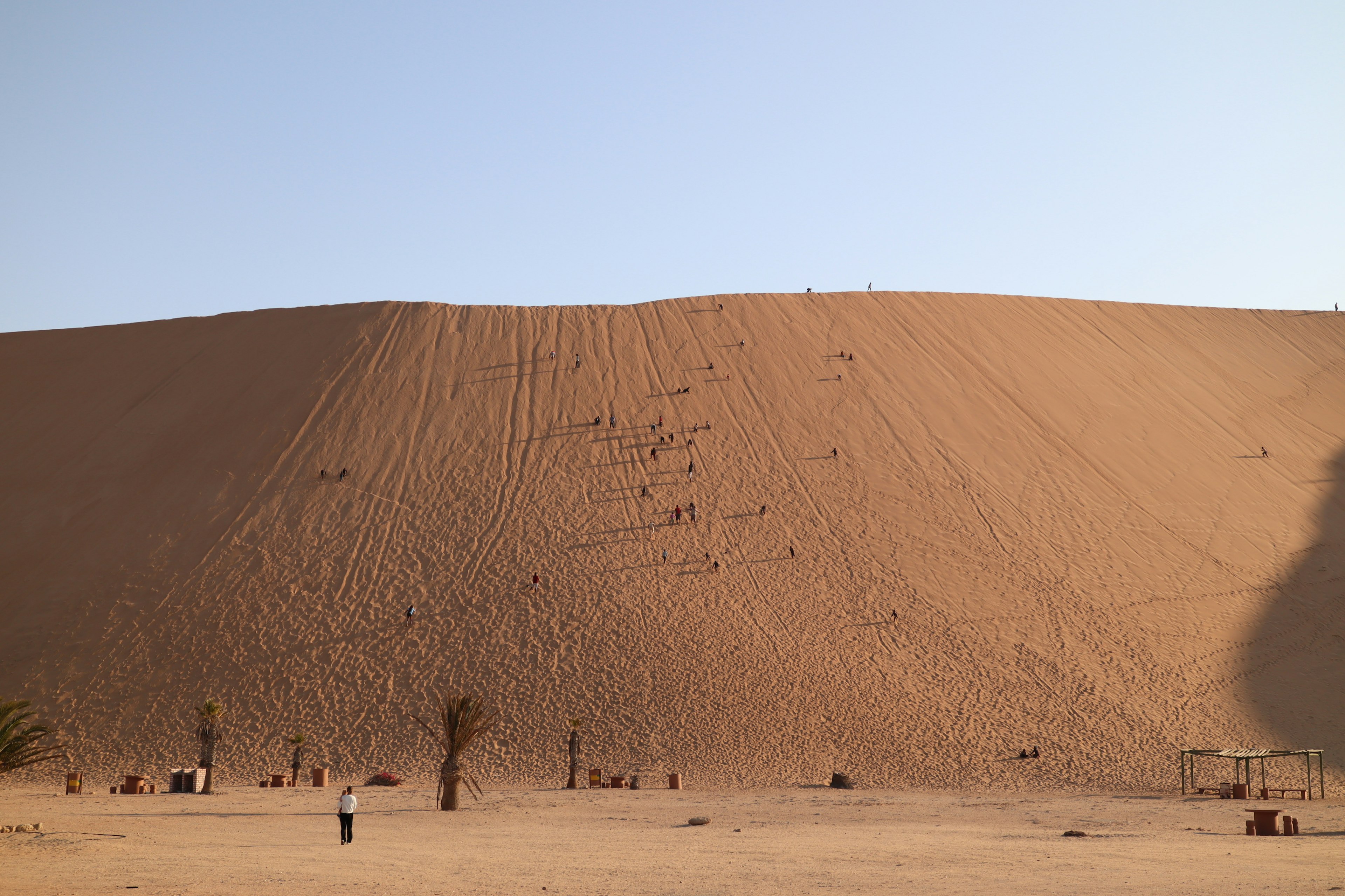 Grande dune de sable avec des personnes marchant à sa base