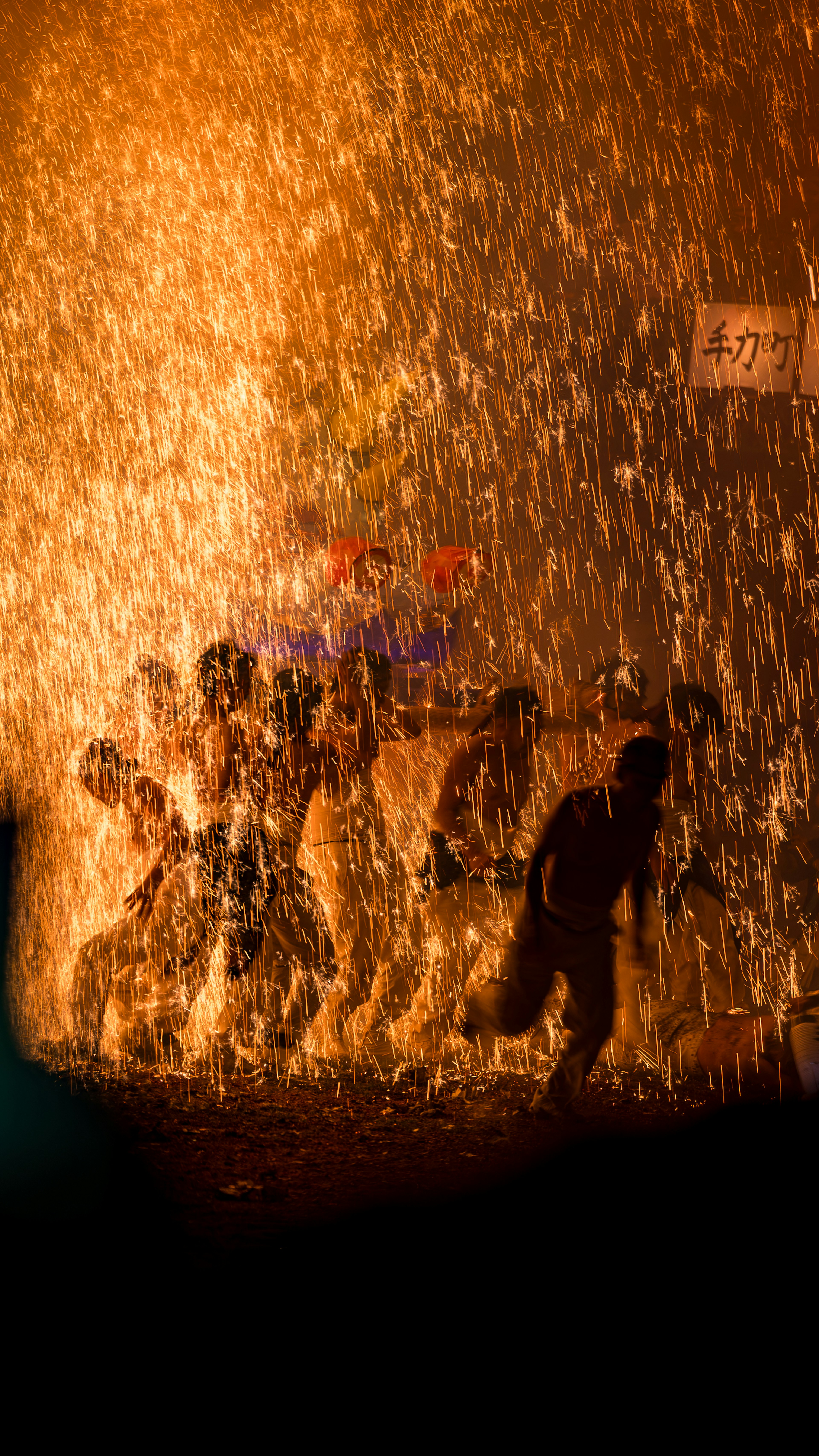 Silhouettes of people running through water spray with orange light