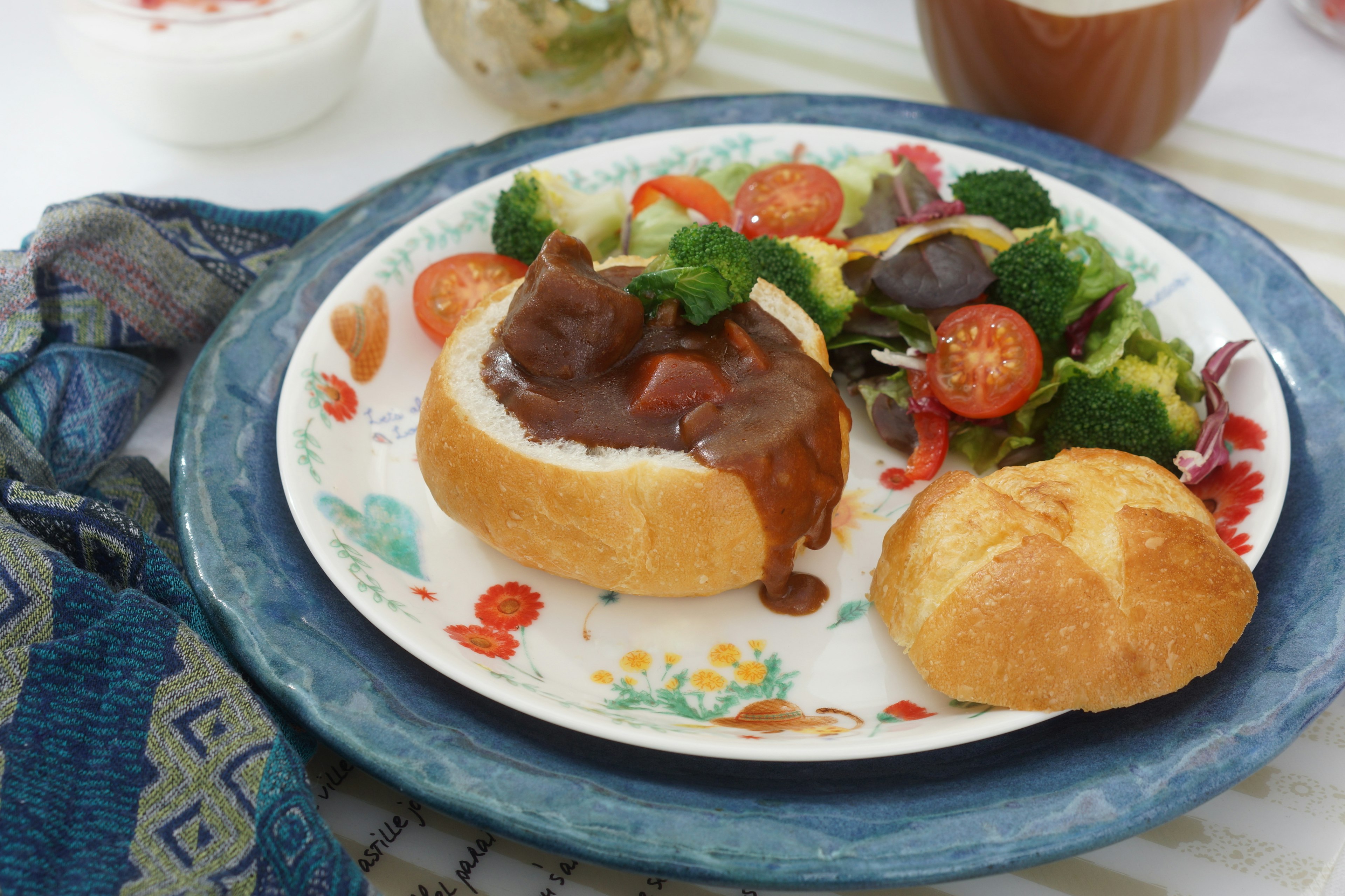 丸いパンに入った肉料理とサラダの皿