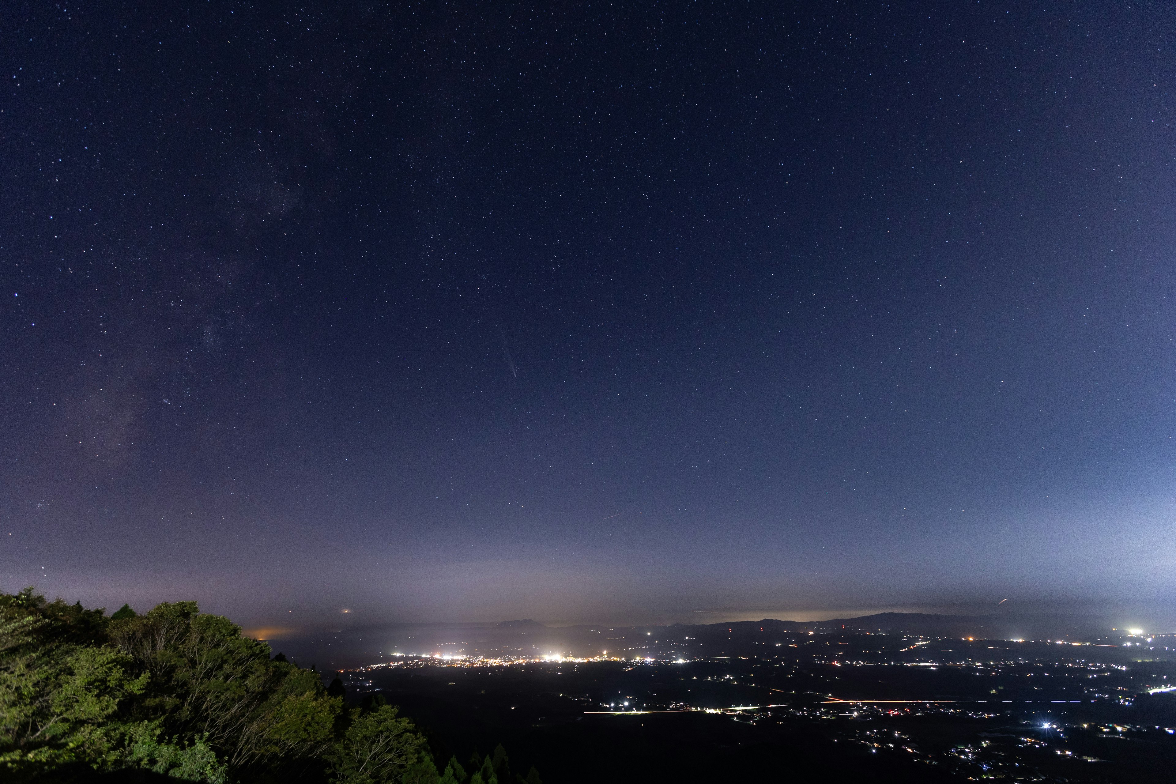 夜空に輝く星と都市の灯りが広がる風景