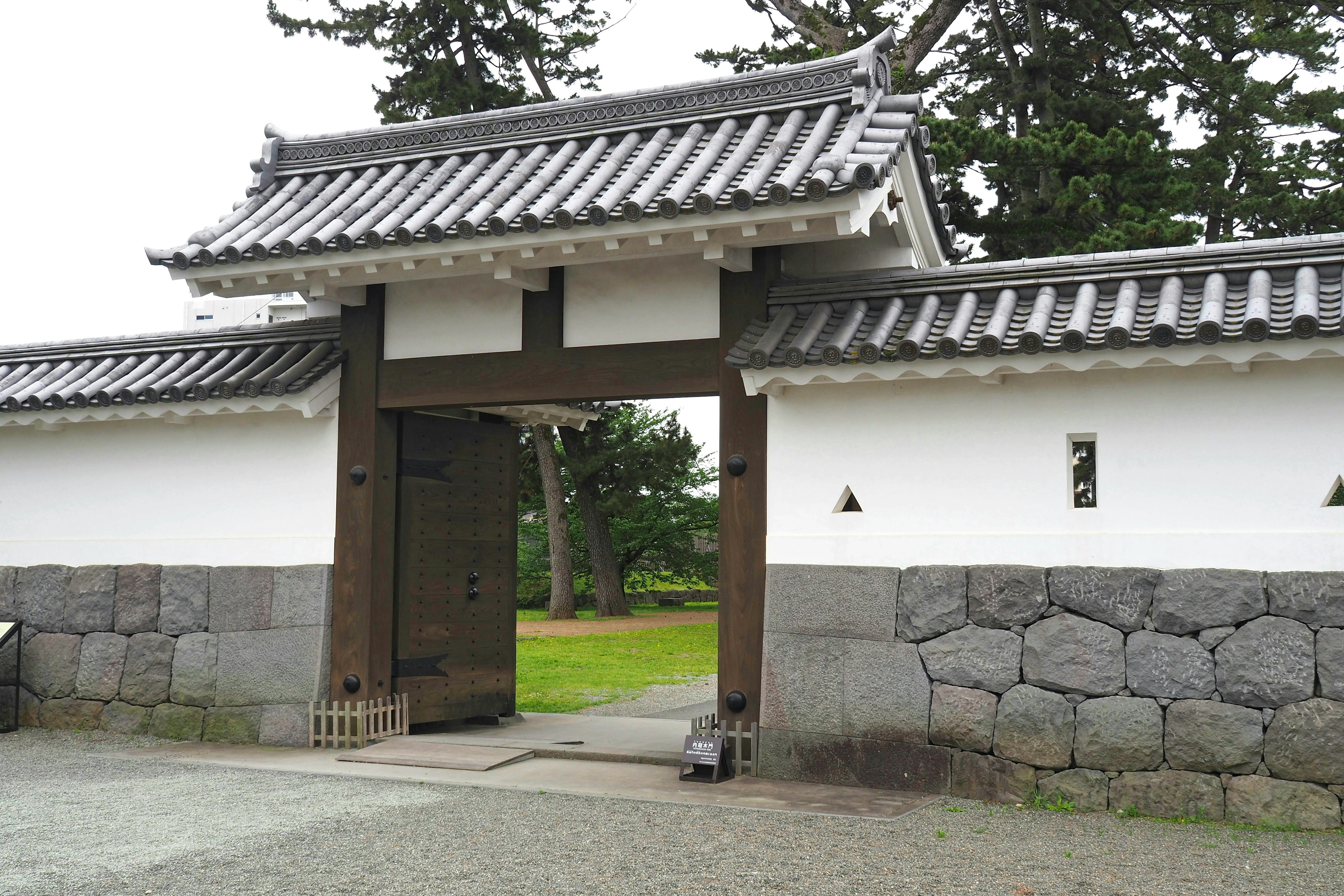 Traditional Japanese gate with stone wall and greenery