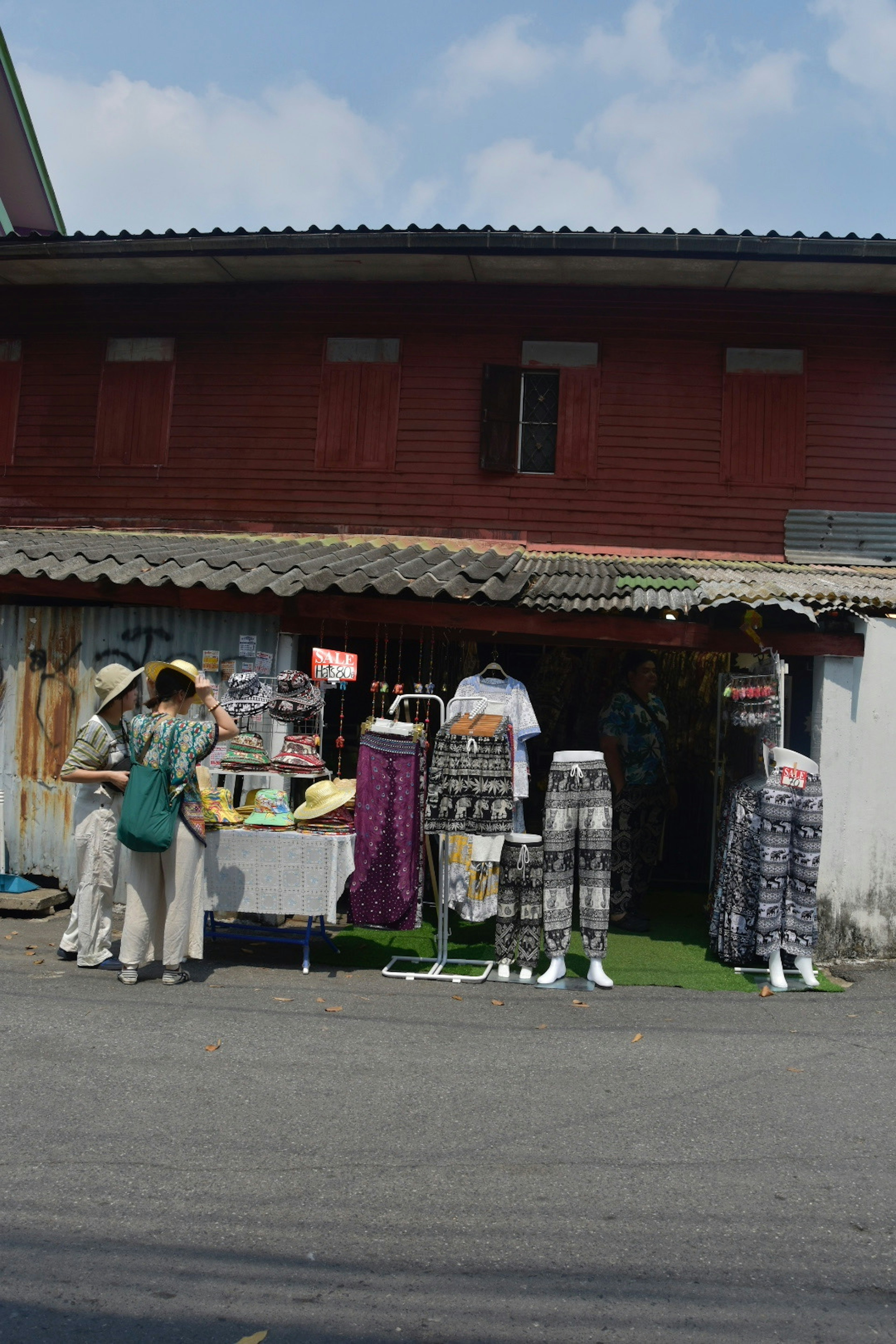 店の前に立つ人々と服が展示された屋外のマーケット