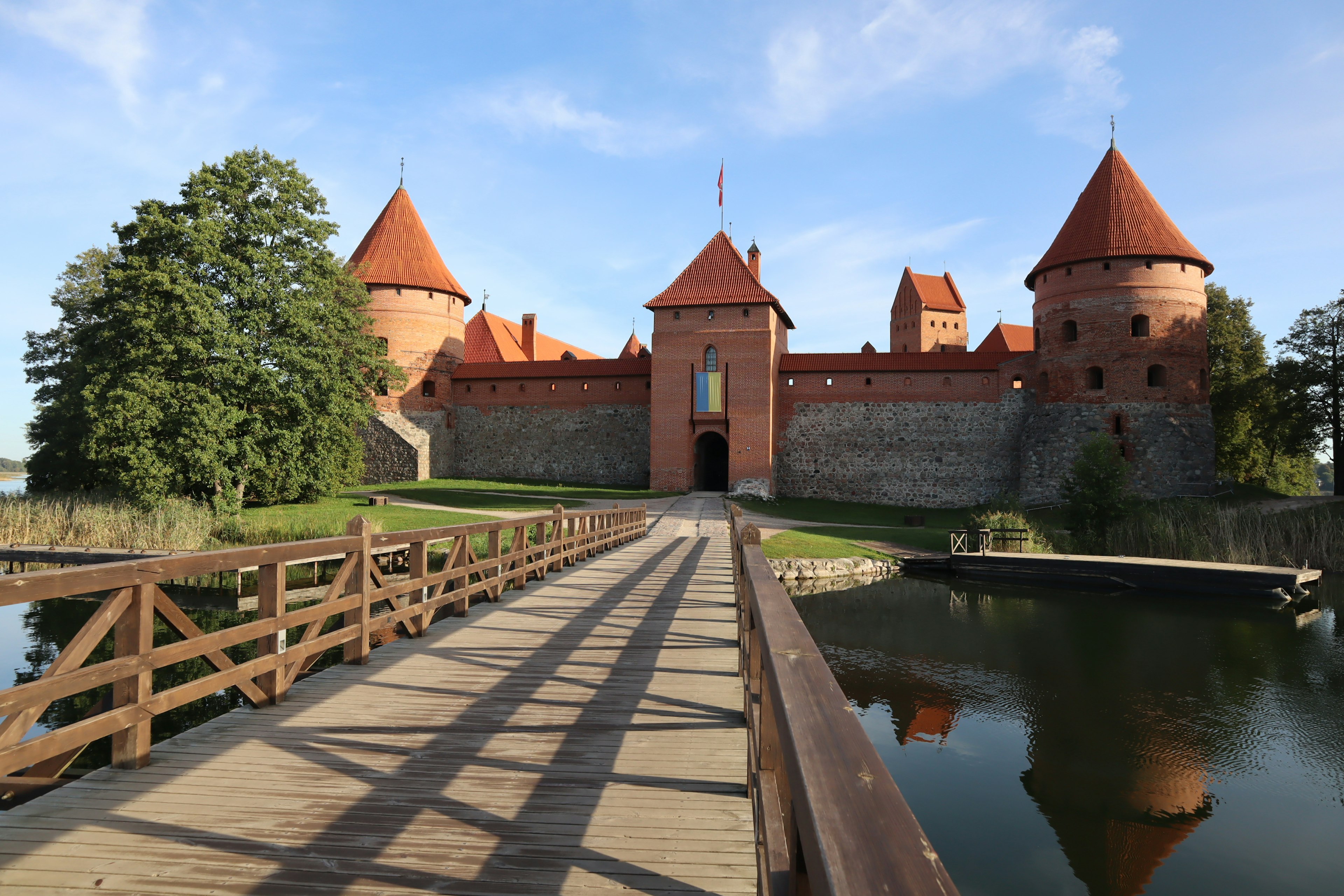 Burg Trakai umgeben von einem See mit einer Holzbrücke im Vordergrund