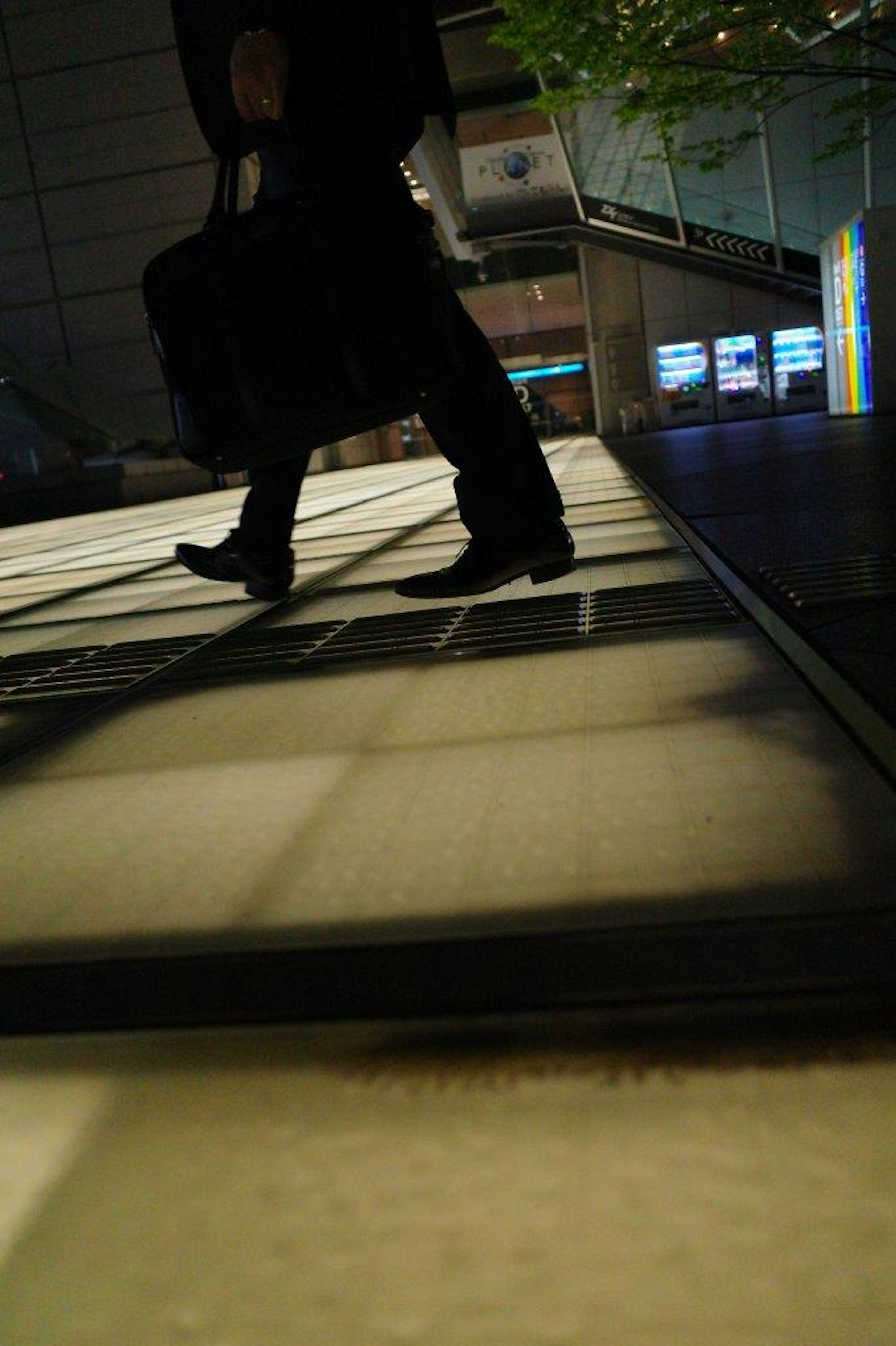 Silhouette di una persona che cammina in un ambiente scuro con contrasto di pavimento luminoso