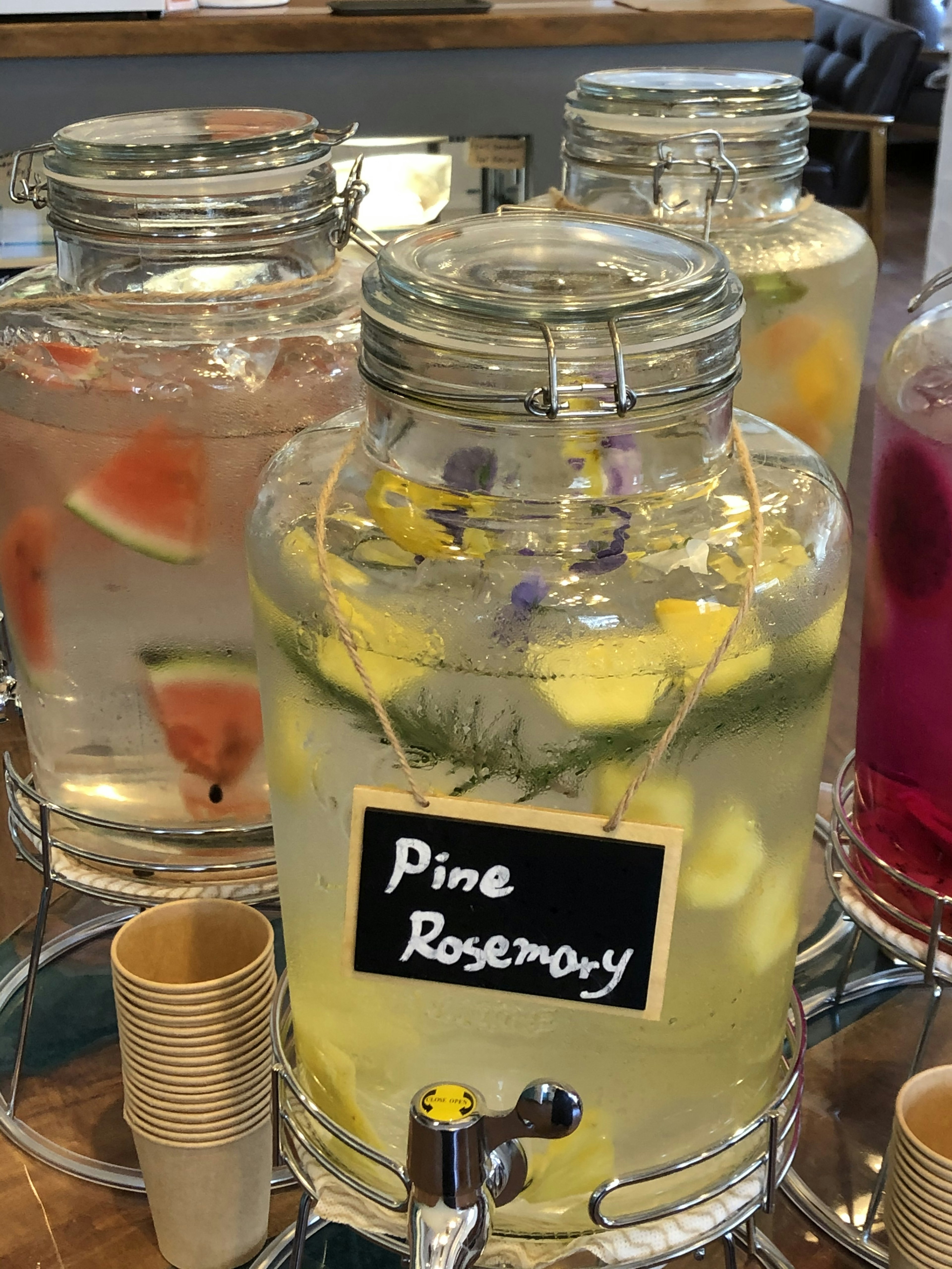 Glass dispensers filled with flavored water featuring lemon and rosemary