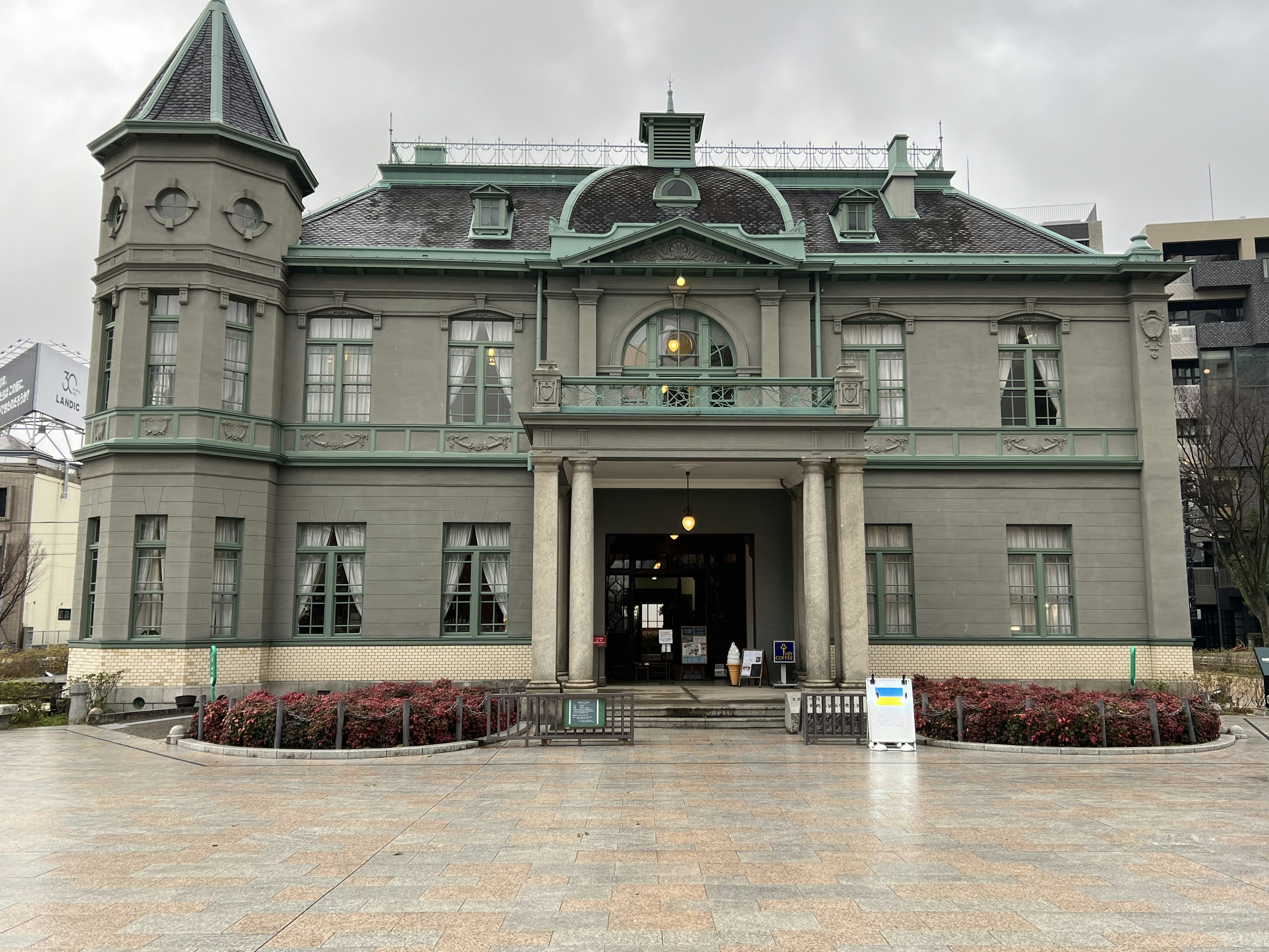 Historisches Gebäude mit grauer Fassade und grünen Akzenten