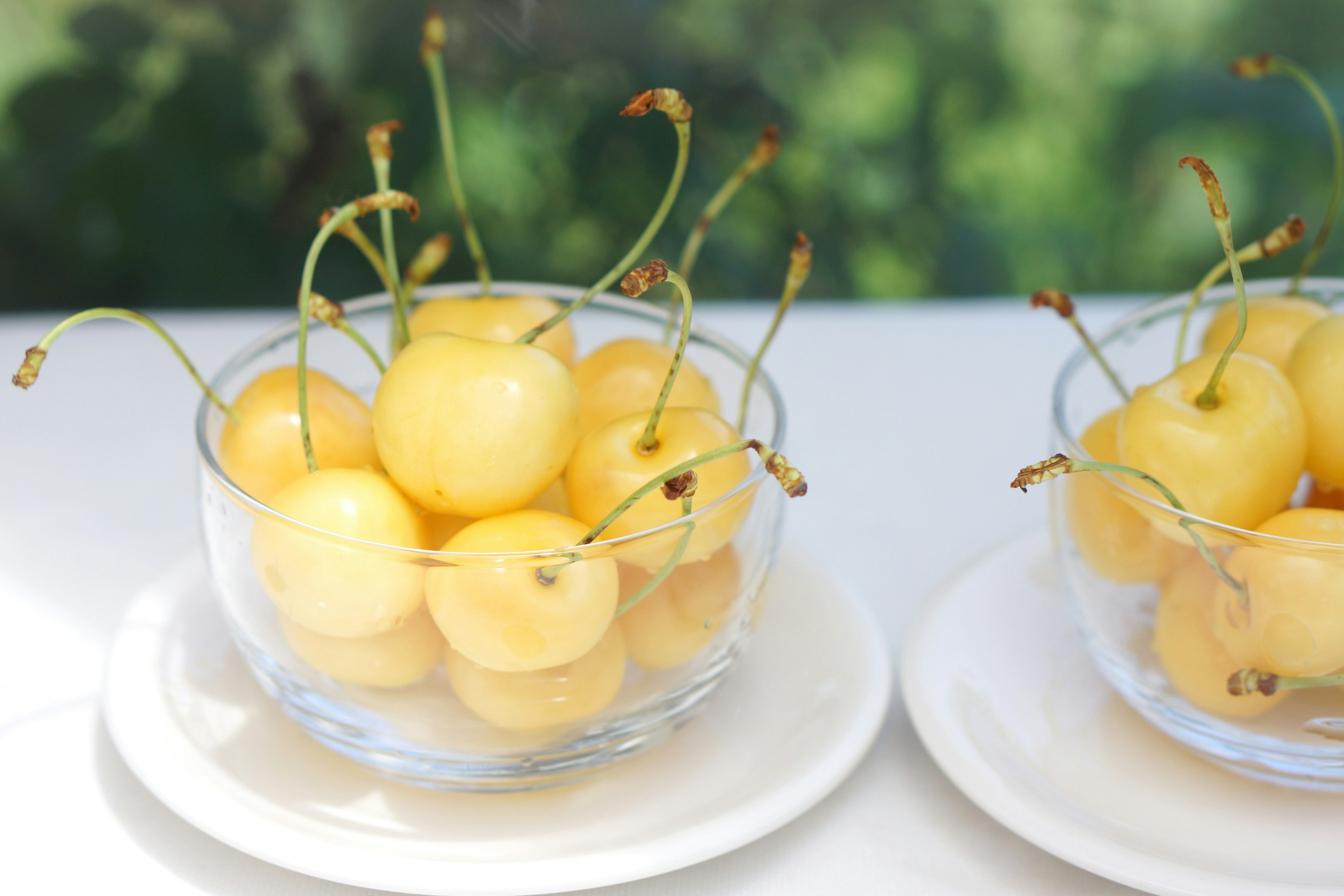 Yellow cherries in a clear bowl with green background