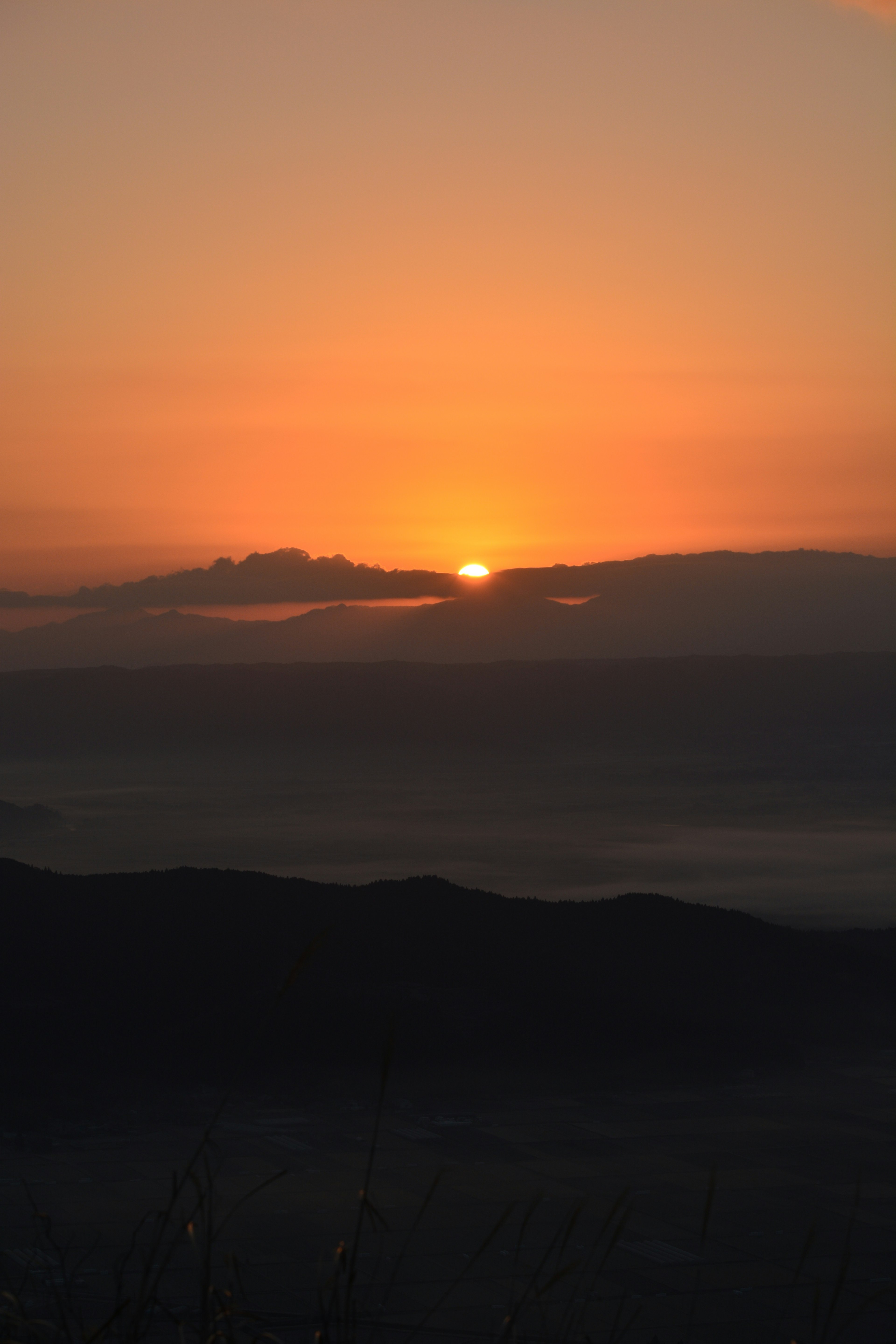 静かな山の上に昇る朝日と柔らかいオレンジ色の空