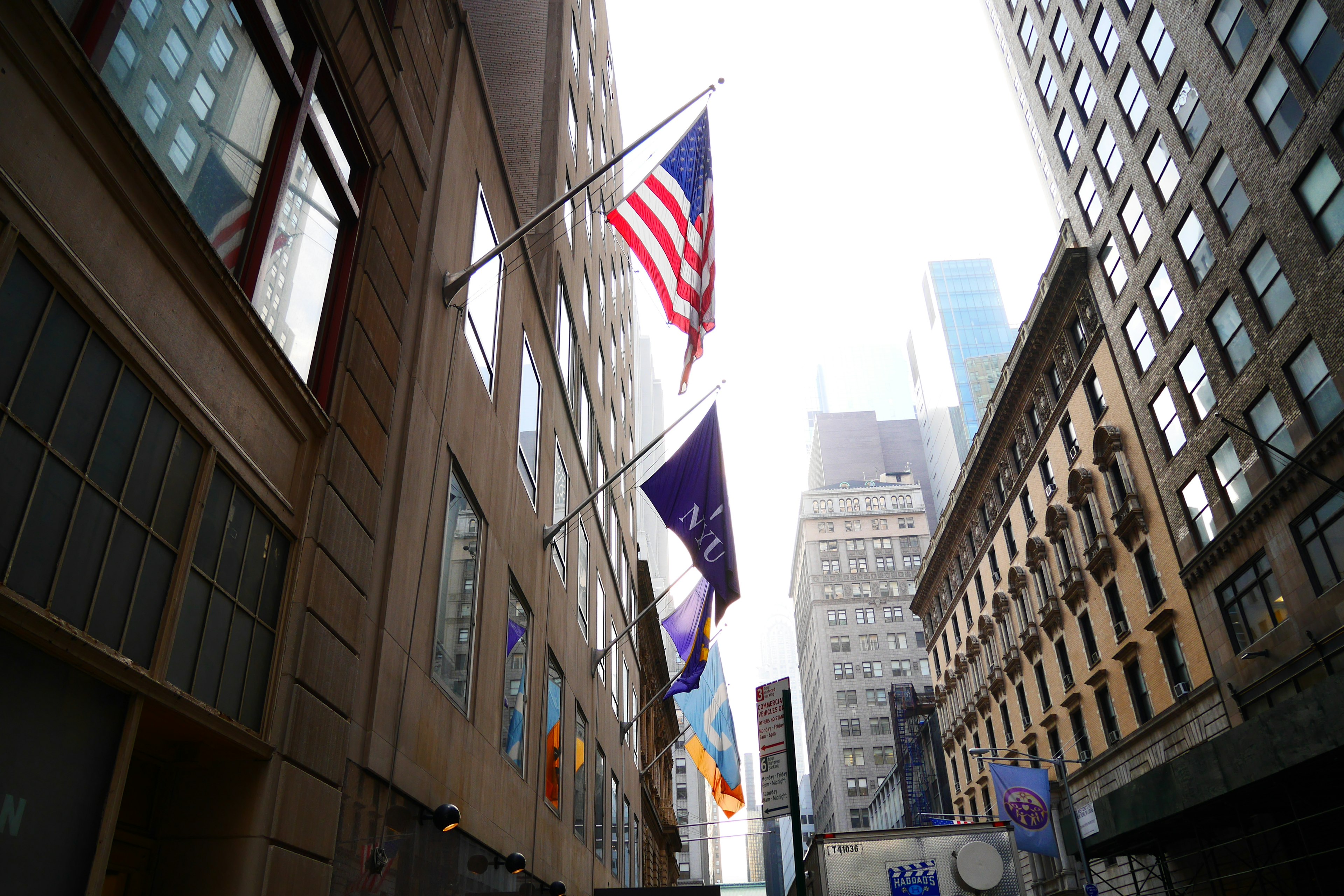 Fachada de un edificio con la bandera americana y varias otras banderas