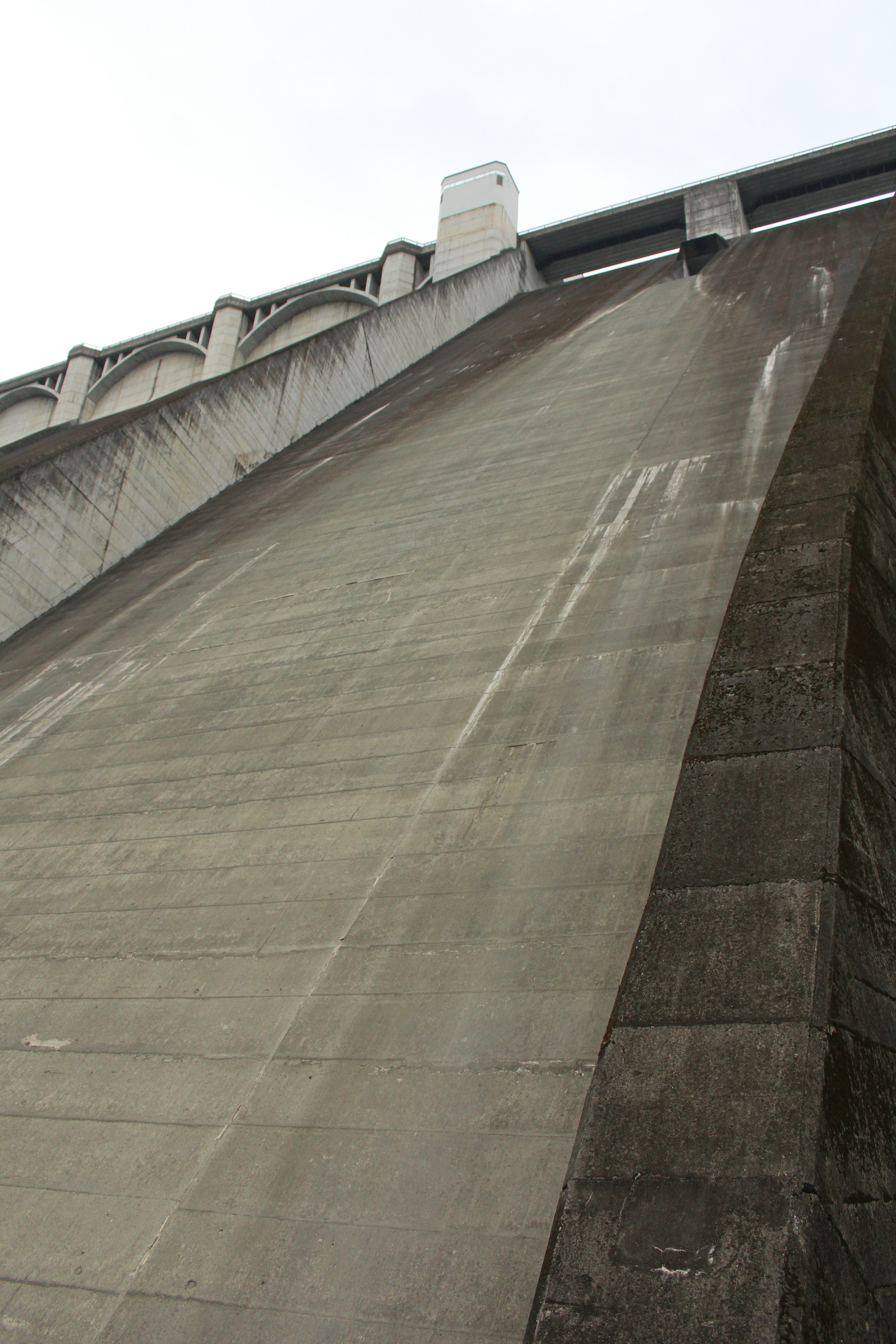 Close-up of a concrete dam's sloped surface showing water streaks