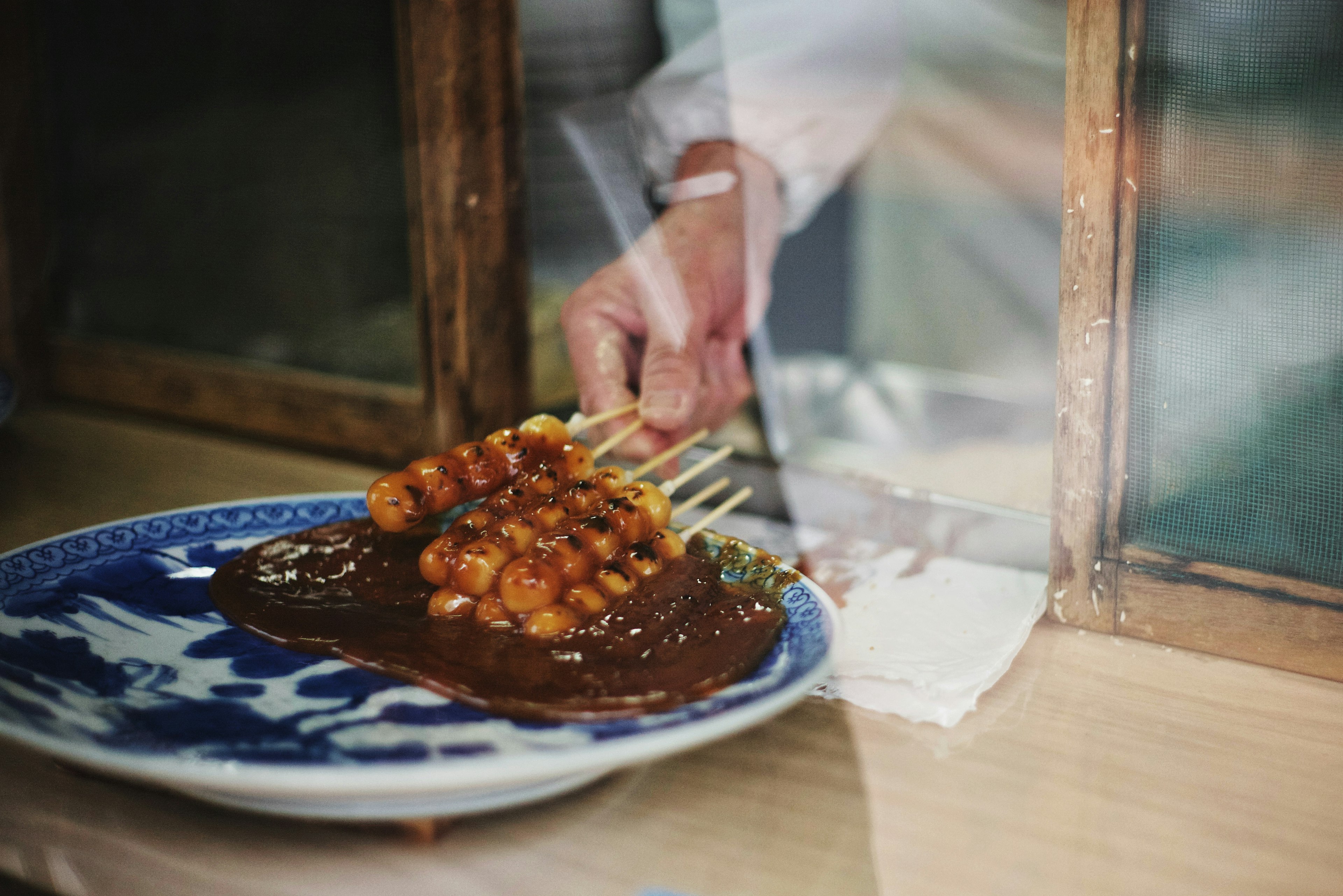 A hand placing skewered food onto a plate