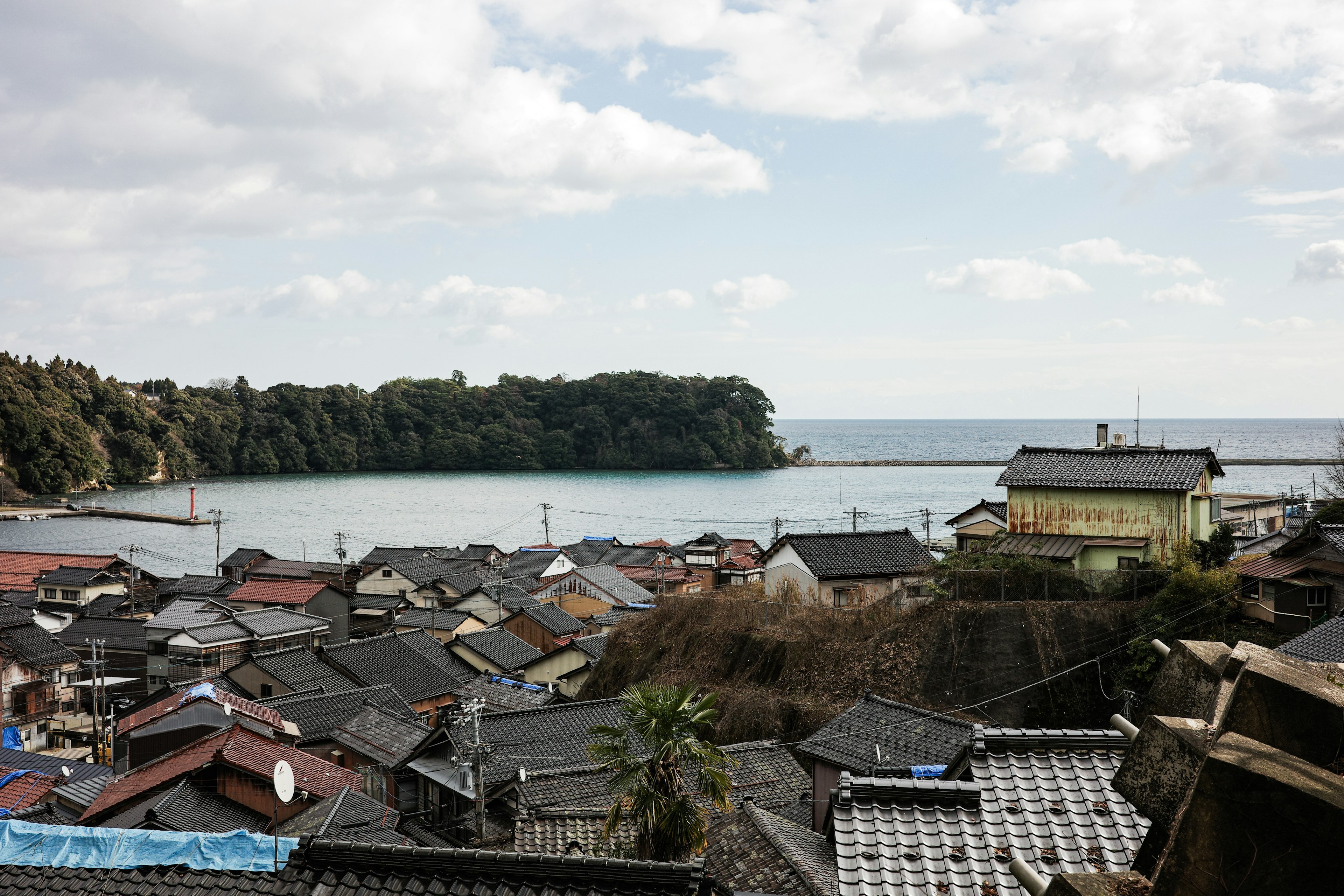 Scenic view of houses and ocean with a cloudy sky