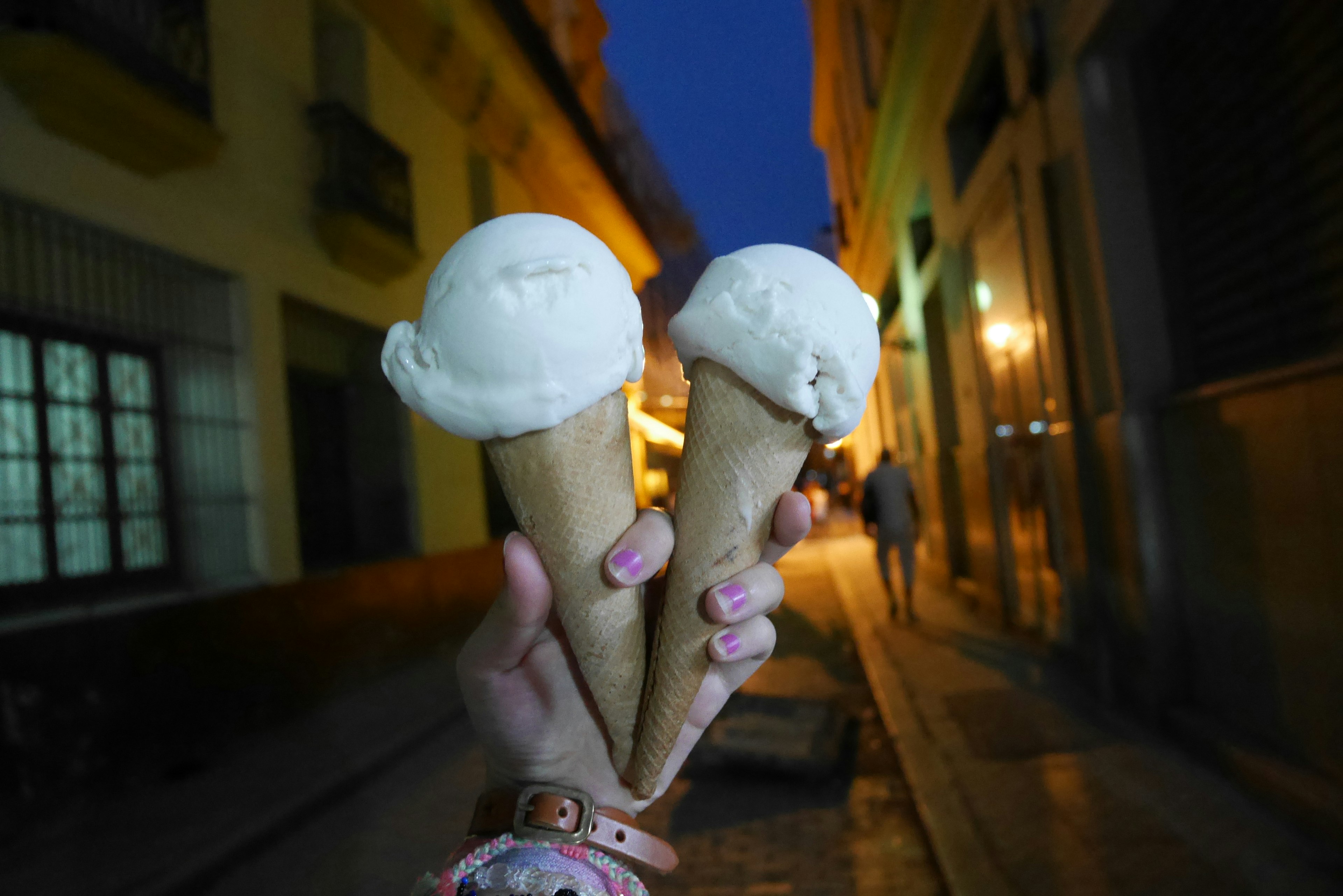 Una mano che tiene due coni di gelato in una strada di notte