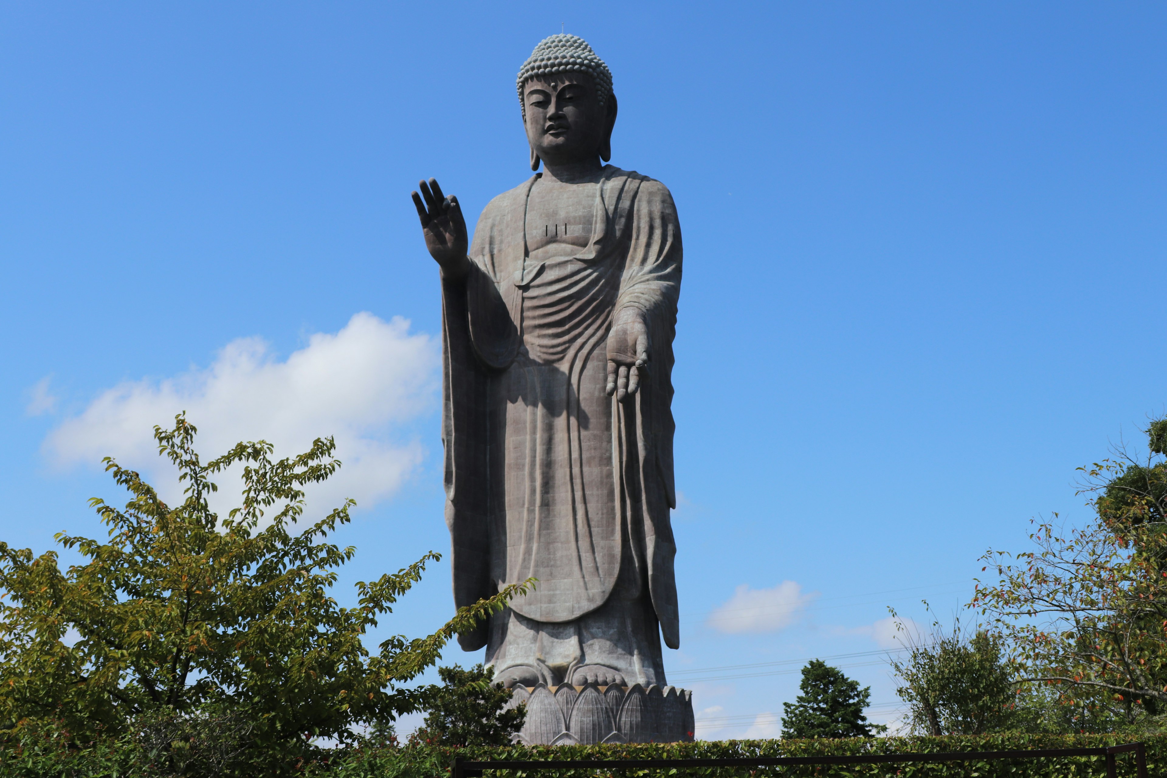 Giant Buddha statue waving under a blue sky