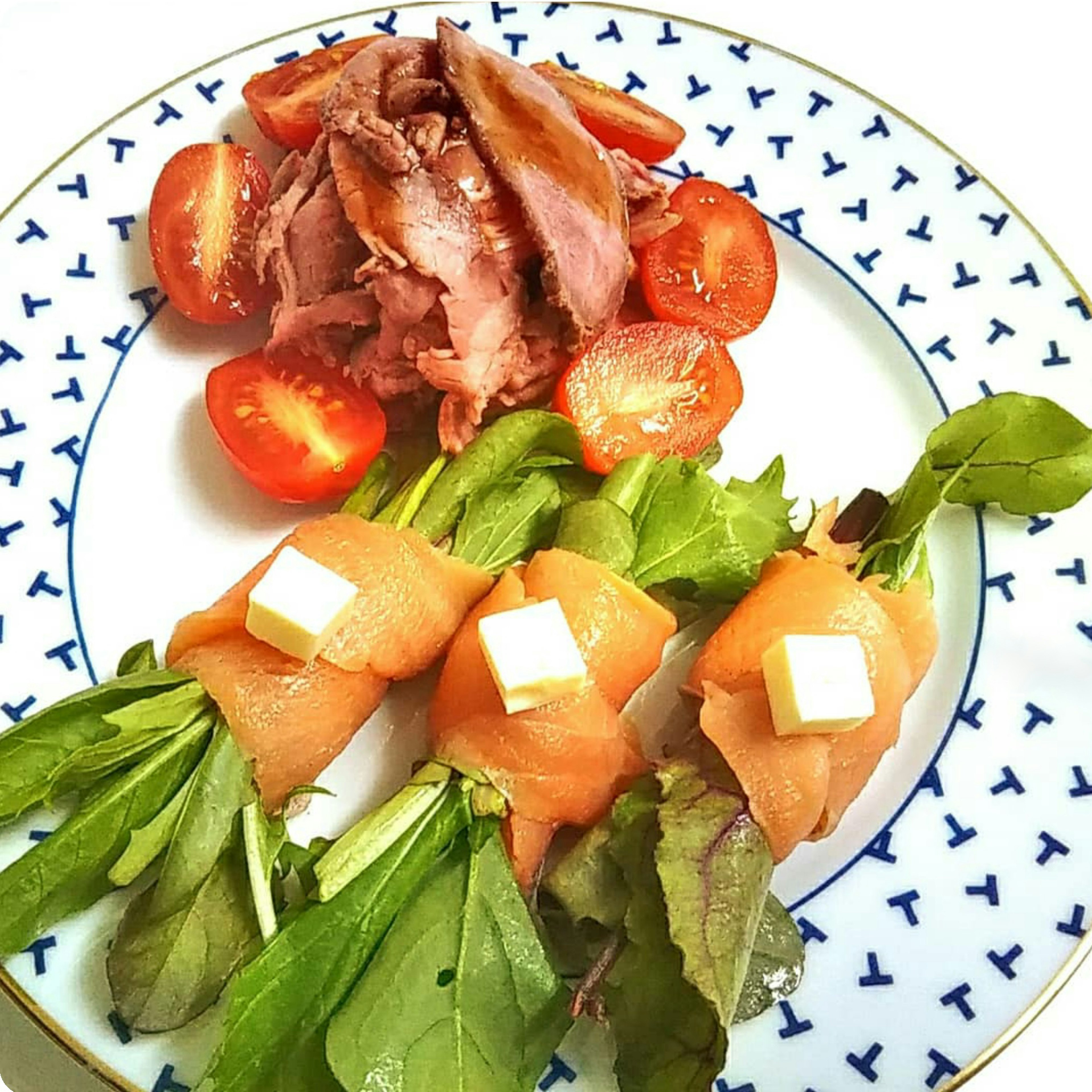 Rouleaux de saumon et de beurre servis avec une salade et des tomates cerises