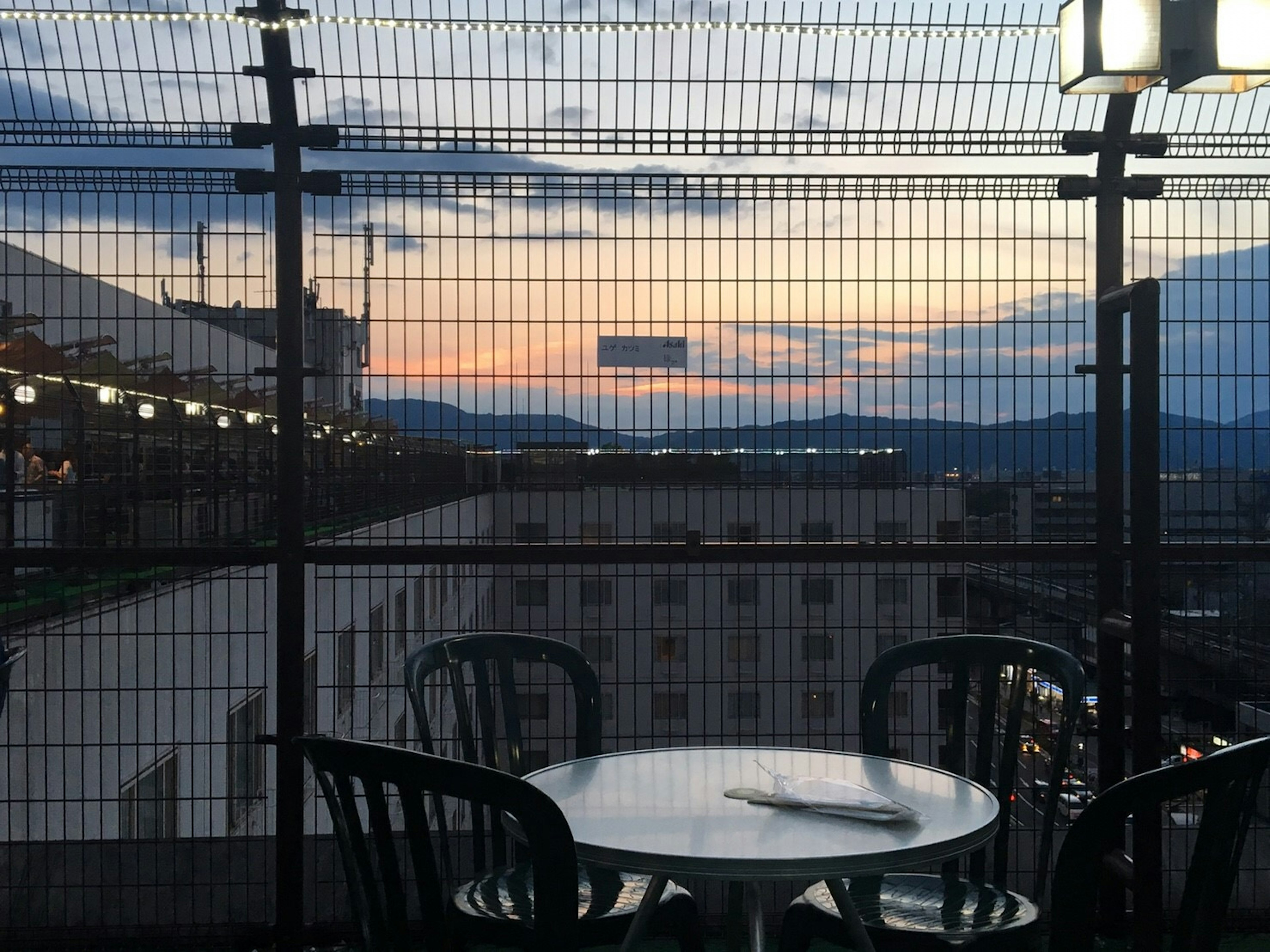 Rooftop terrace with a table and chairs overlooking a sunset