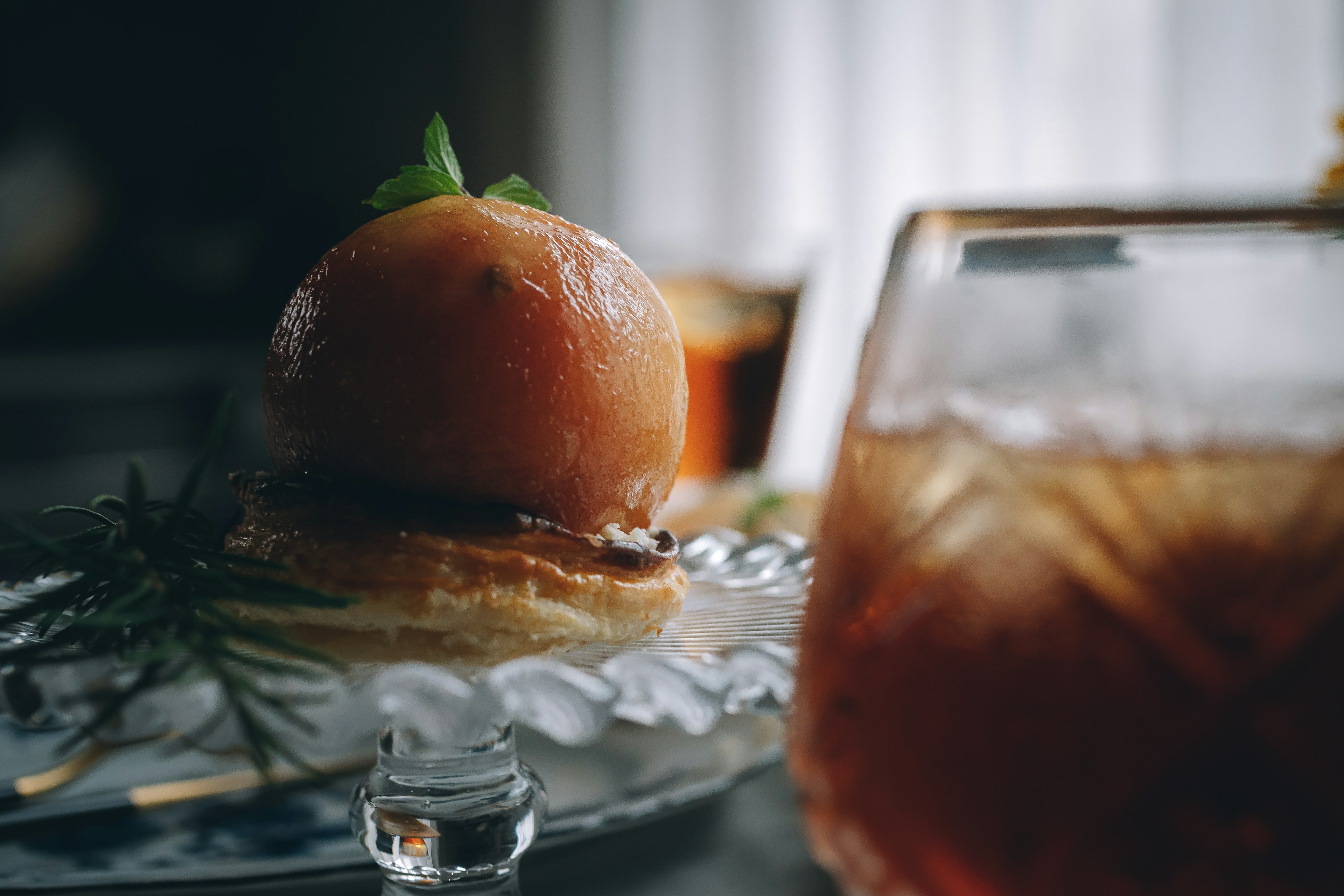 Una hermosa presentación de postre y cóctel con una fruta parecida a un durazno coronada con una hoja de menta