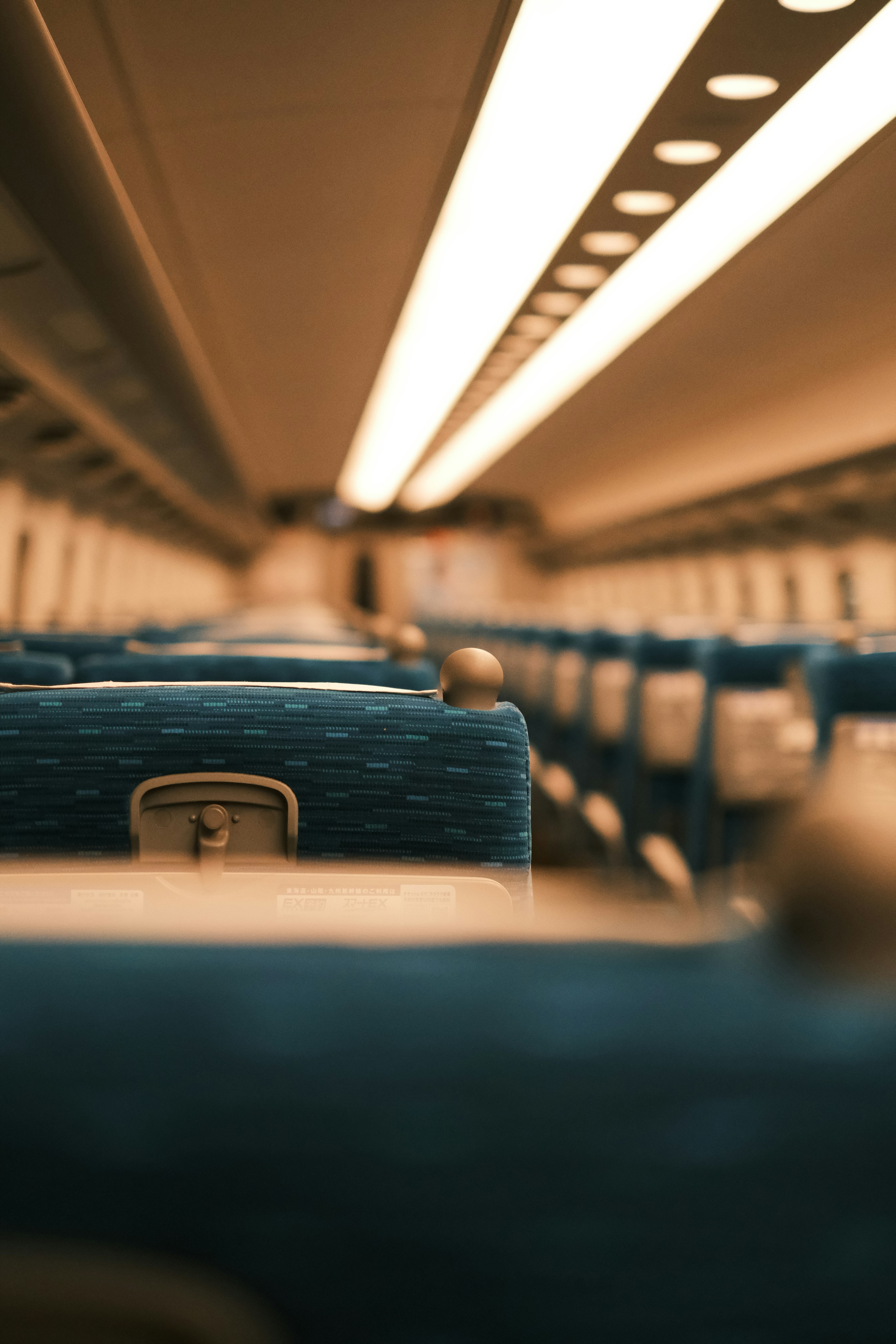 Interior view of a train with blue seats and overhead lights