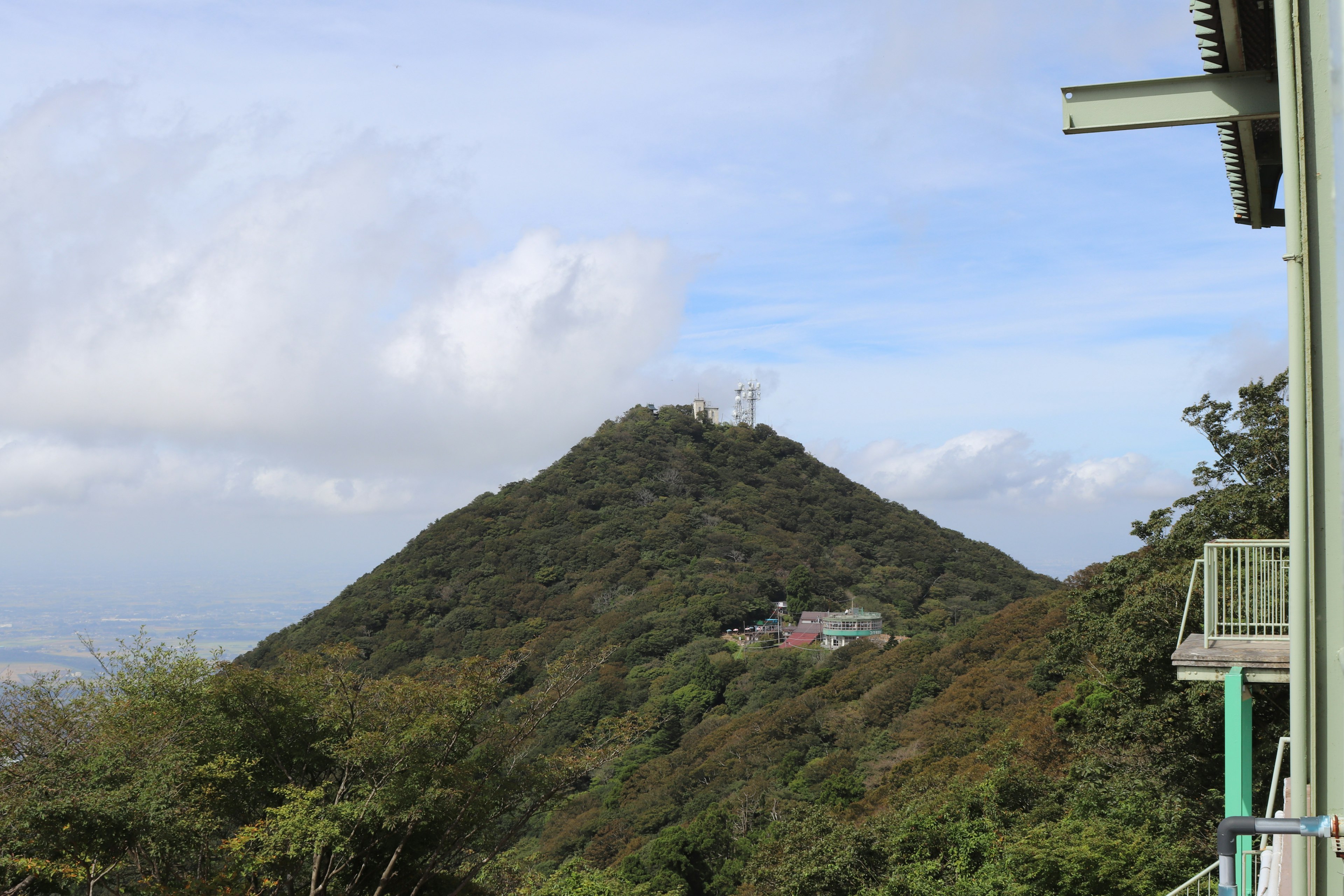 Vista di una montagna verde con un piccolo edificio sotto un cielo azzurro