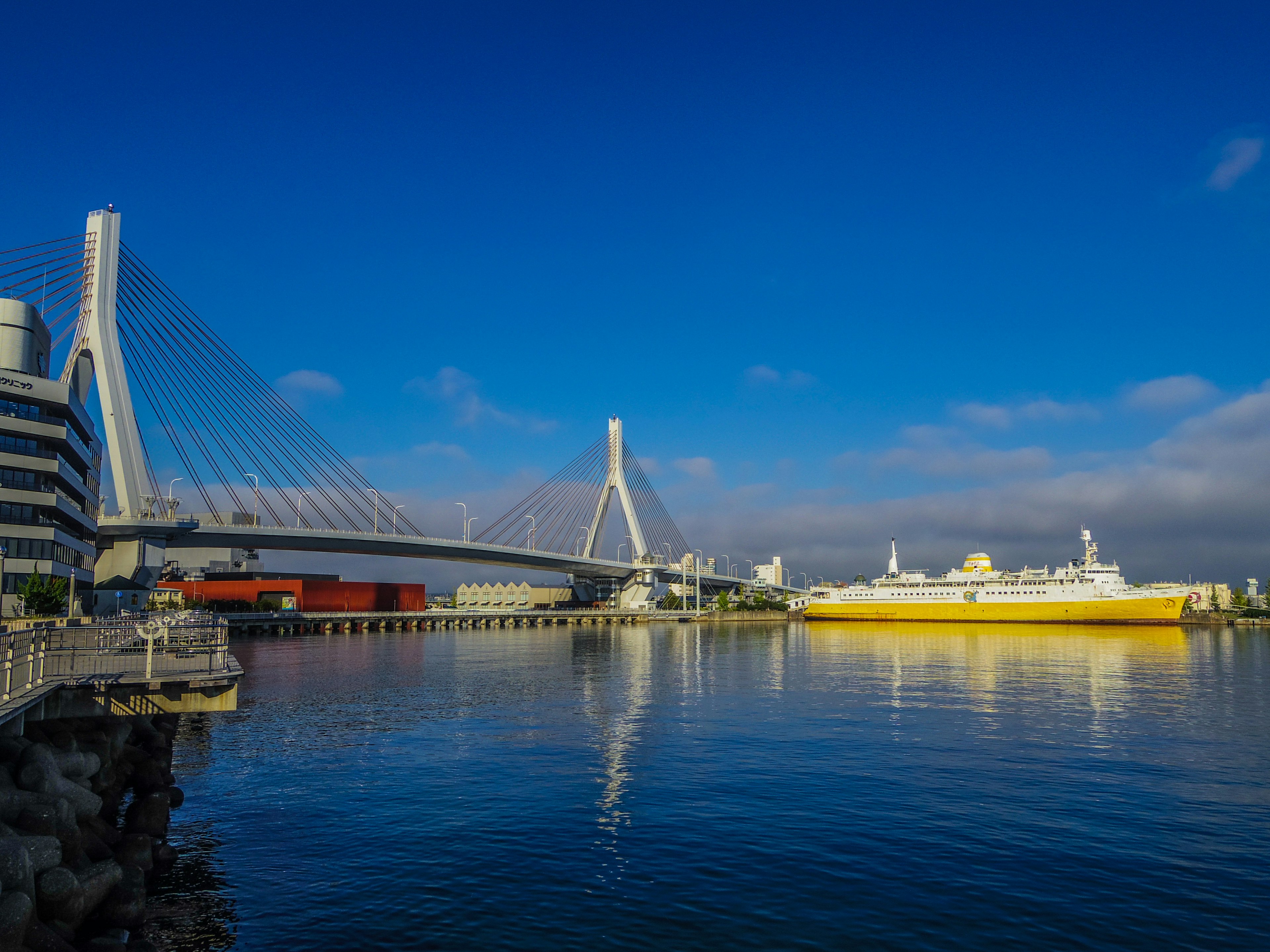 Vista panoramica di un ponte e una nave sotto un cielo blu Bella riflessione sulle calme acque del porto