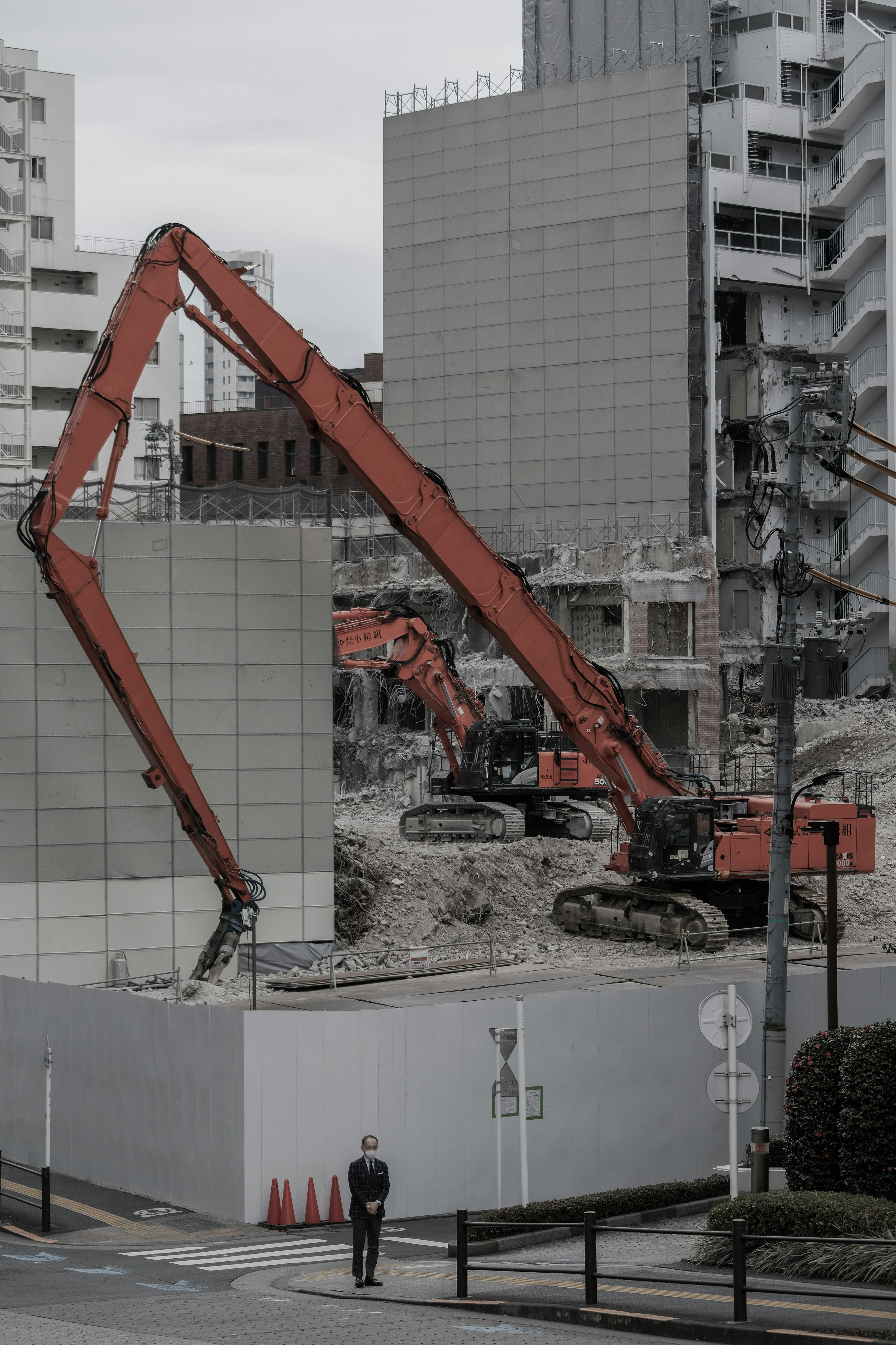 Construction site with two orange excavators and surrounding buildings