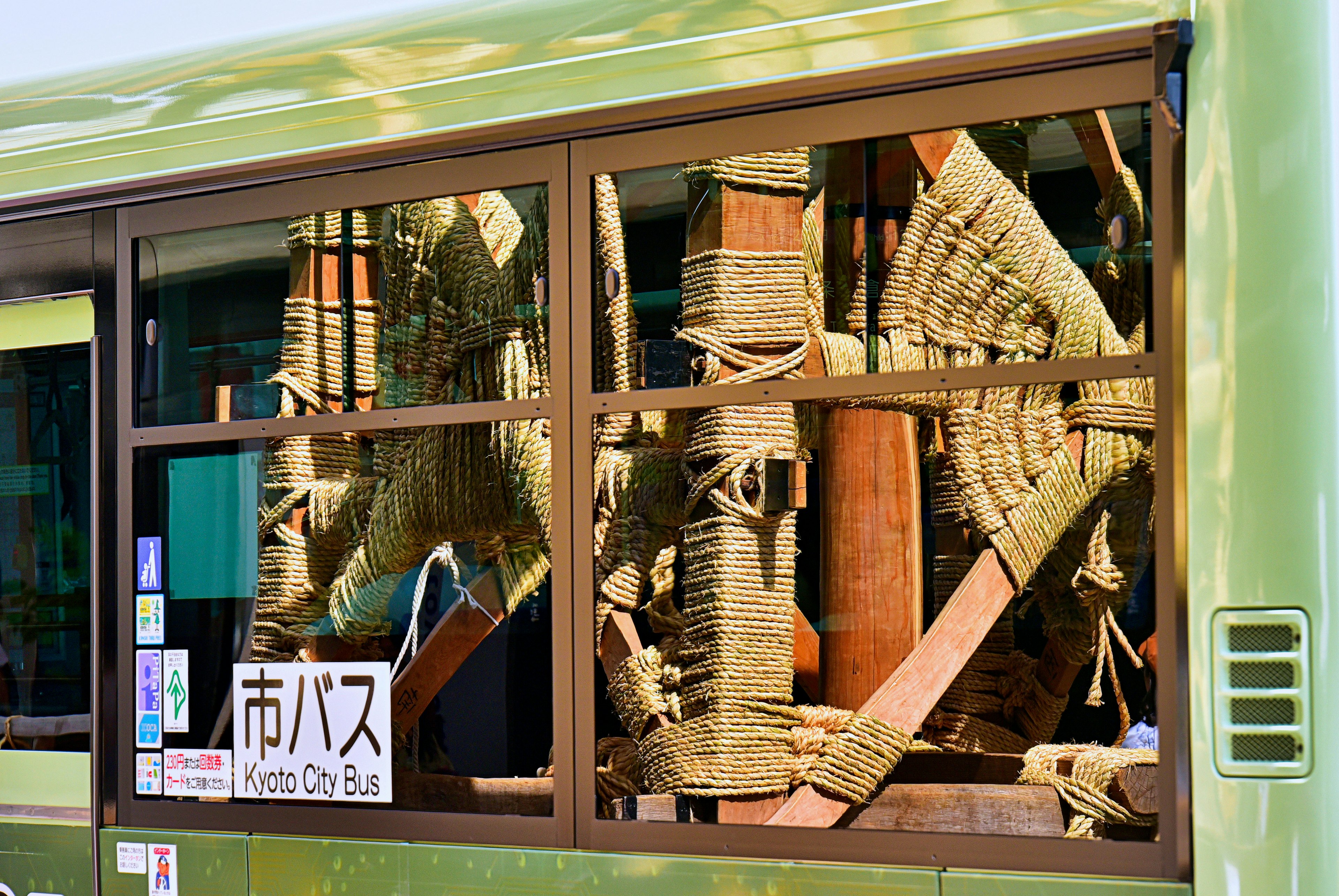 Vue à travers une fenêtre de bus montrant des structures en bois et de la corde