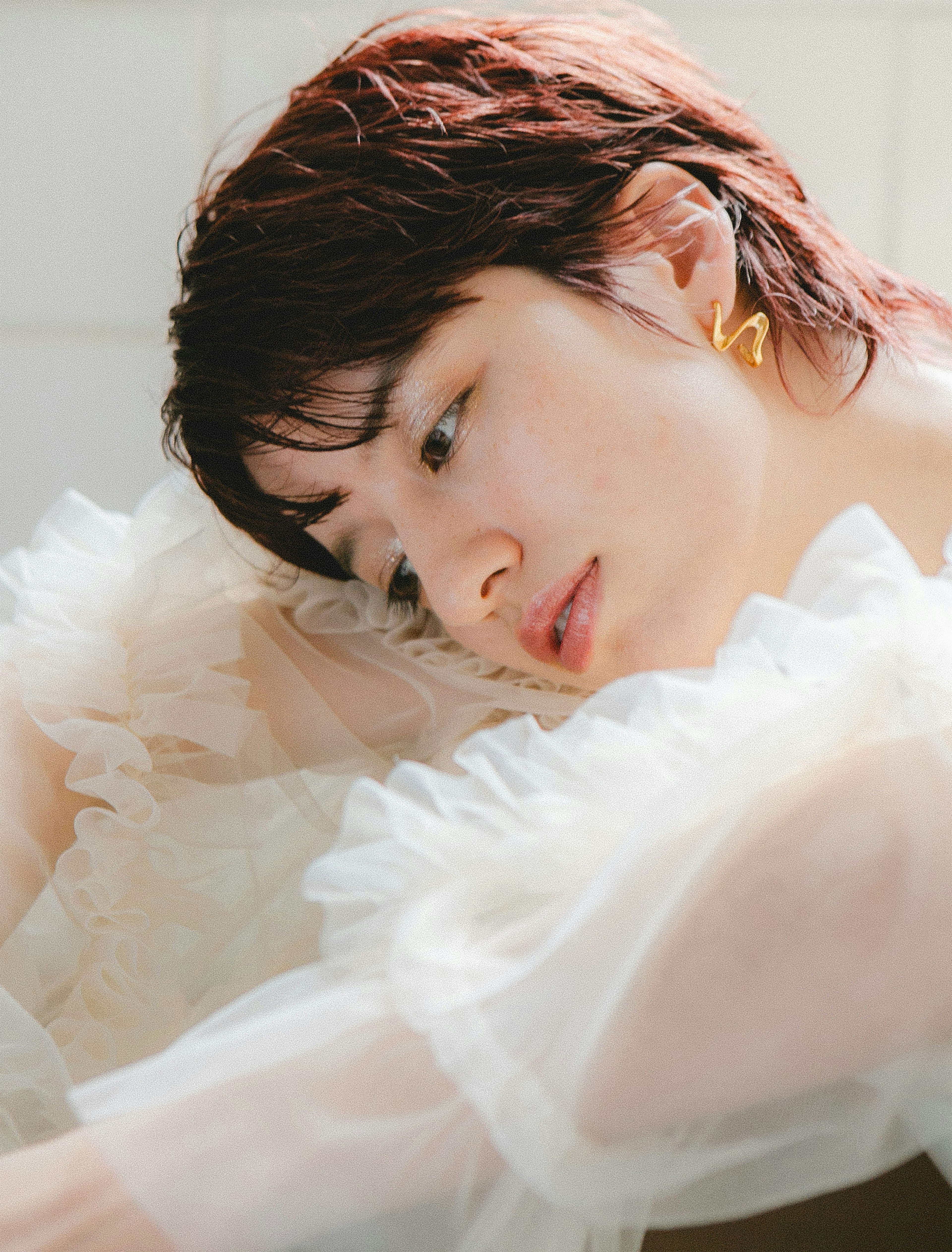 A woman wearing a light-colored ruffled blouse is looking to the side