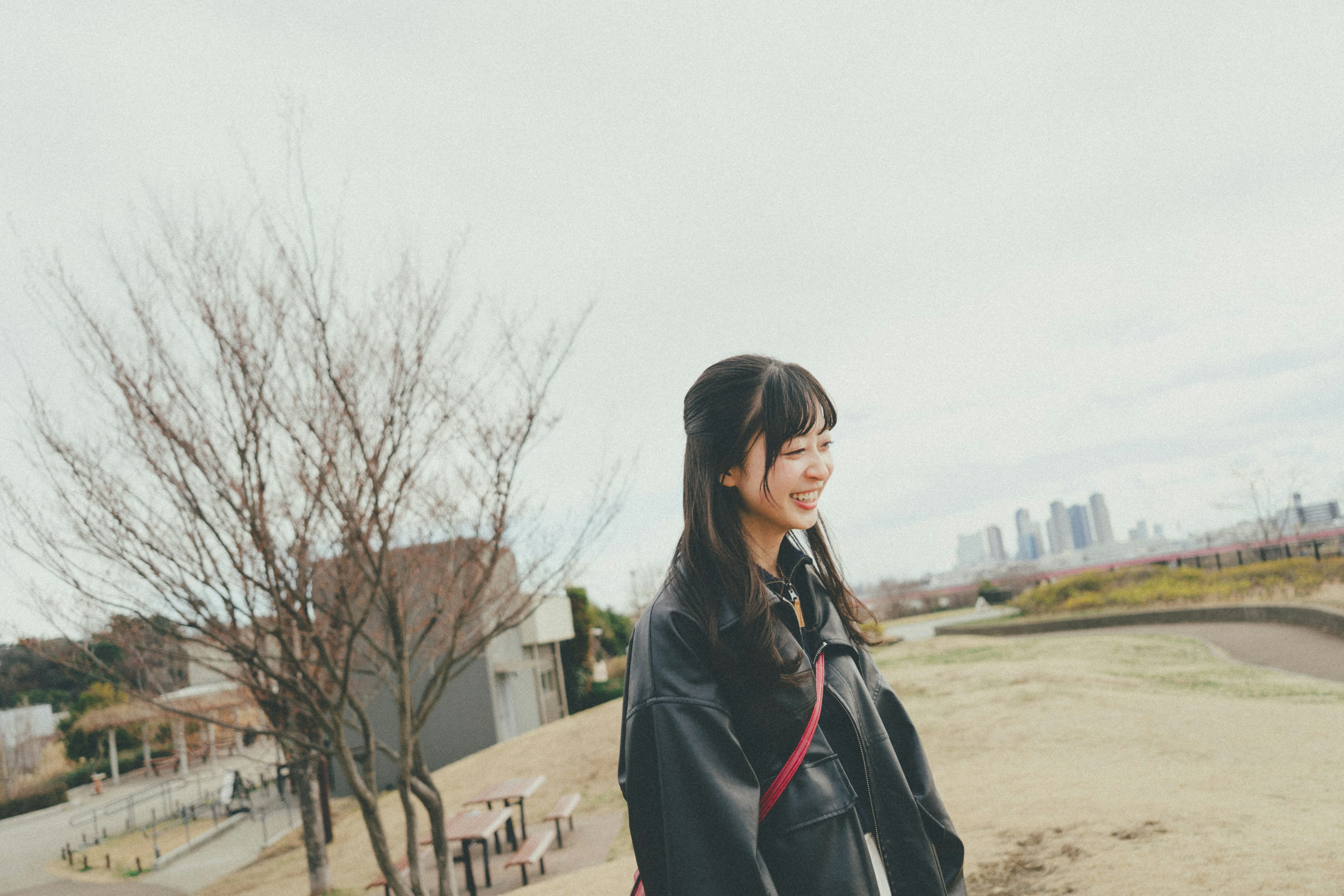 Una mujer sonriendo en un parque con un horizonte urbano de fondo