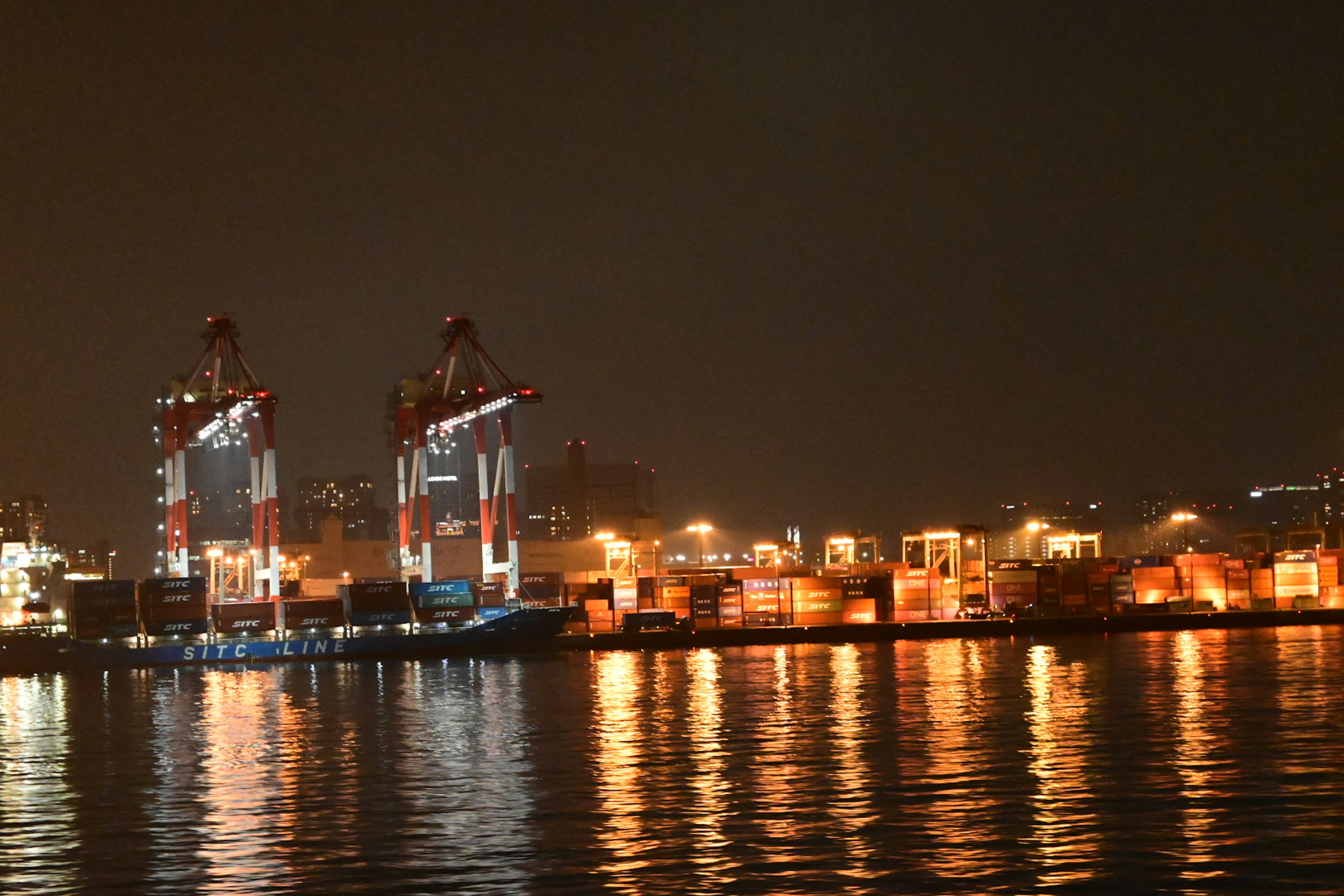 Nighttime view of a port with illuminated cranes and containers