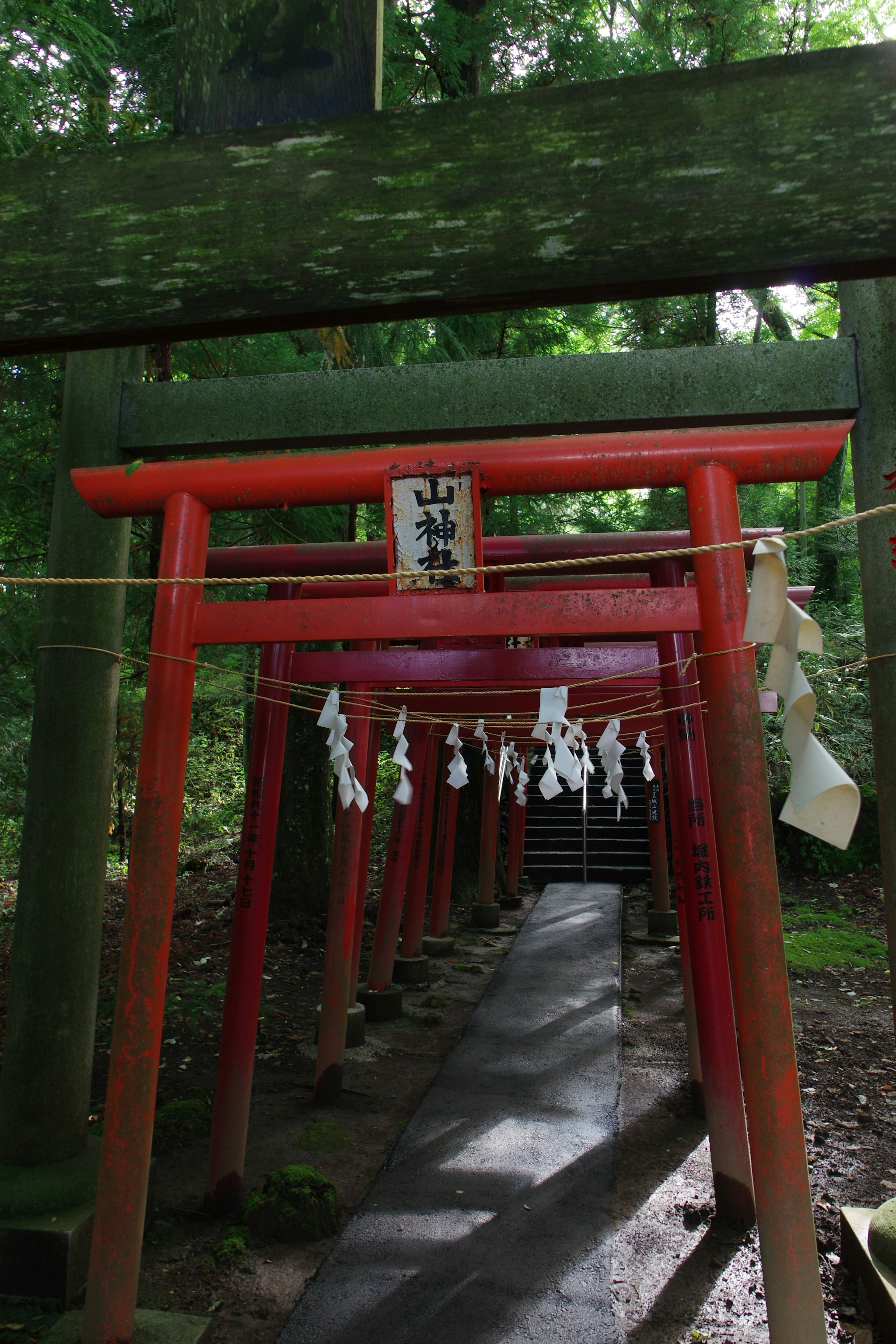 Un chemin bordé de torii rouges et un panneau de sanctuaire