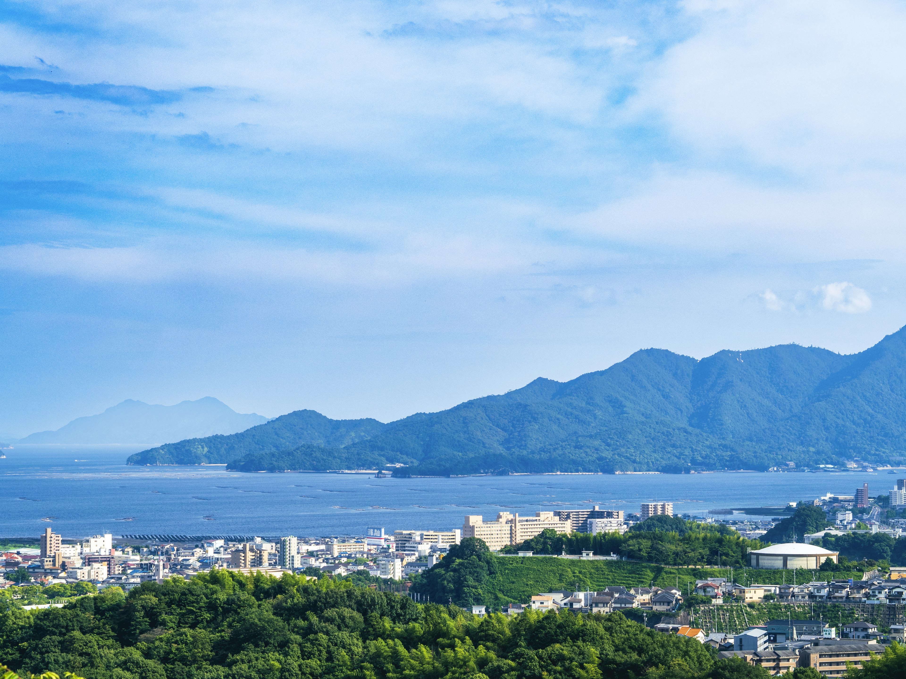 Vue panoramique de montagnes et de la côte sous un ciel bleu avec un paysage urbain et une végétation luxuriante