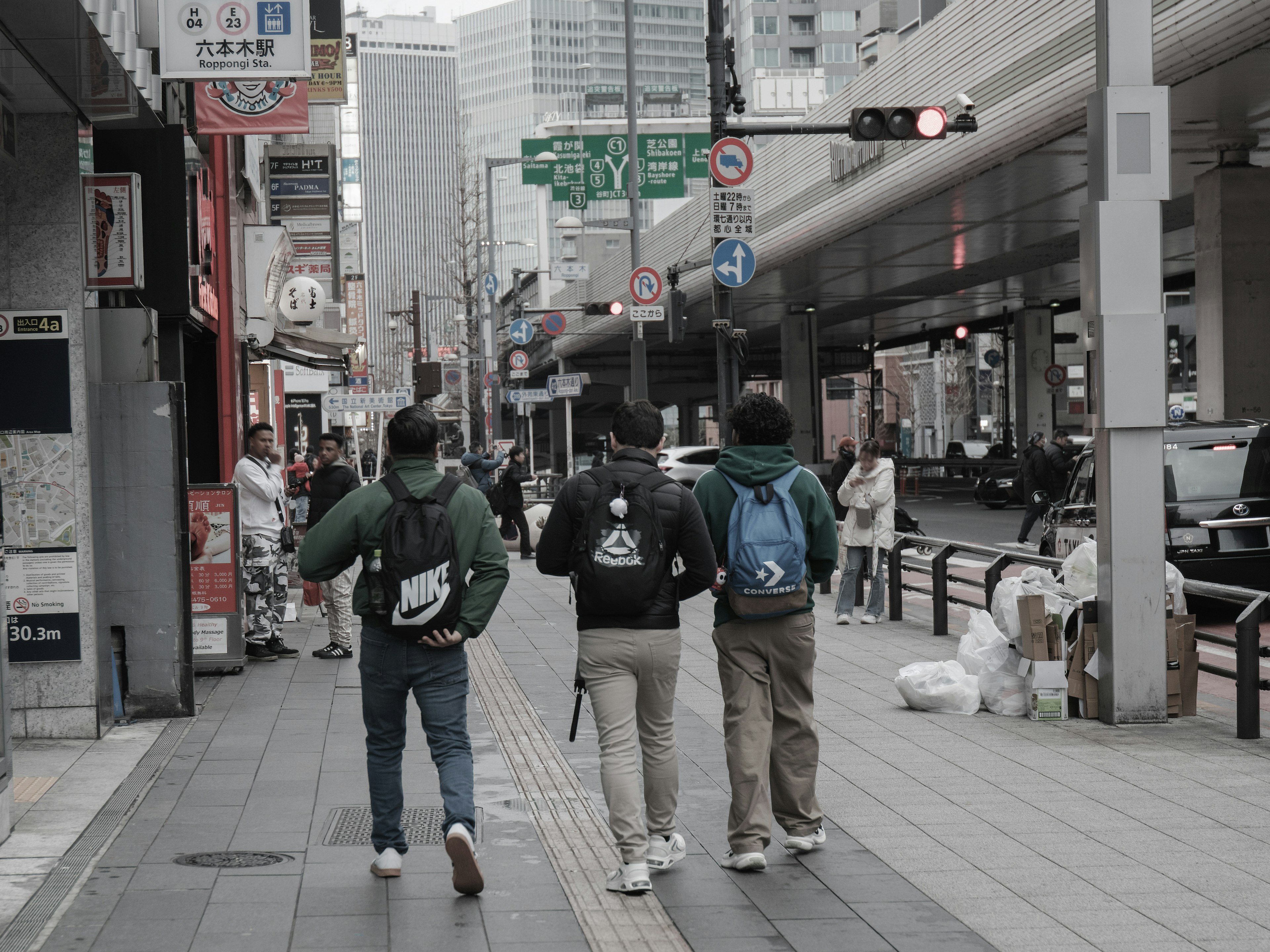 Three men walking on a city street wearing backpacks urban setting