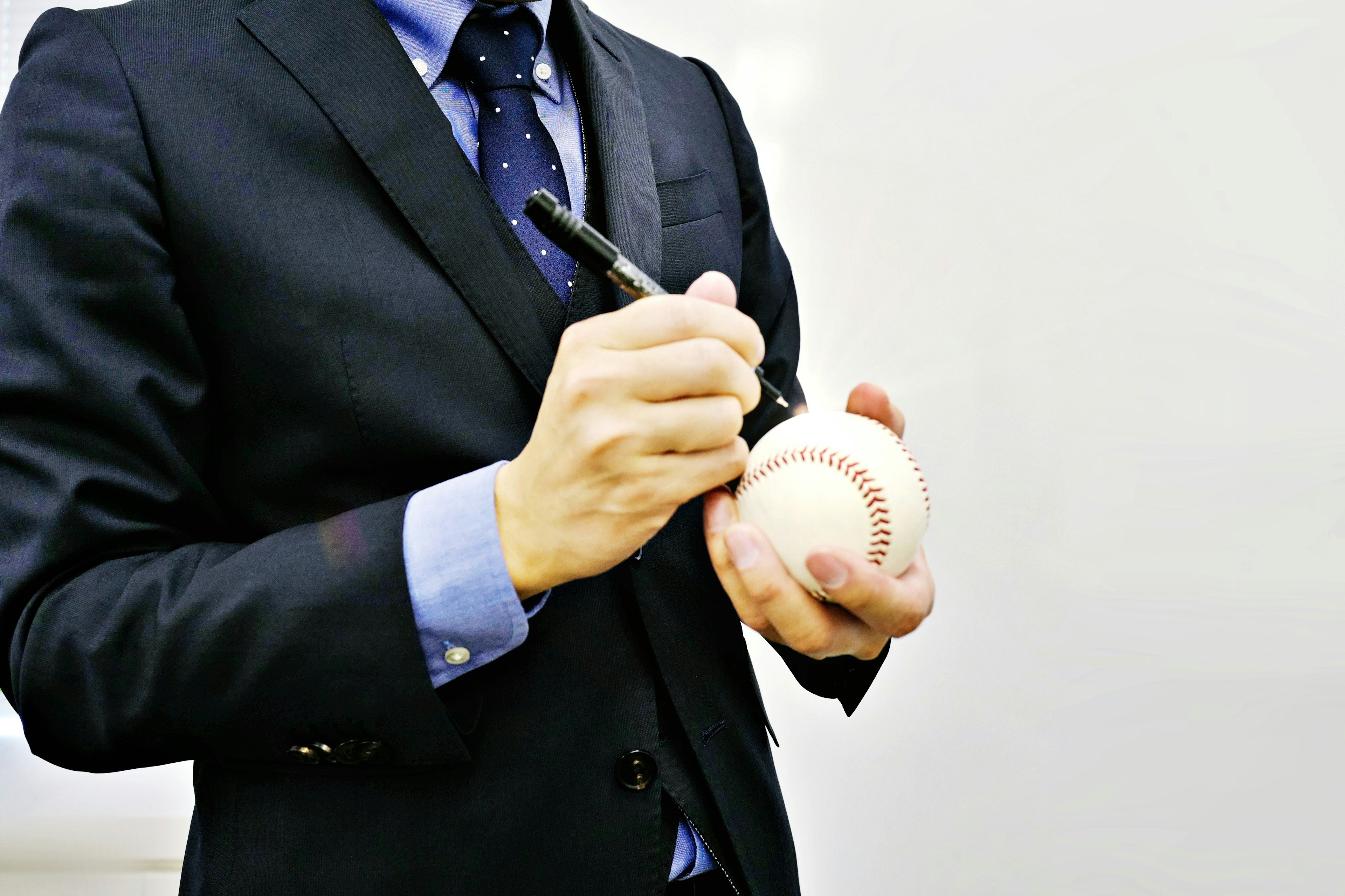 A man in a suit signing a baseball