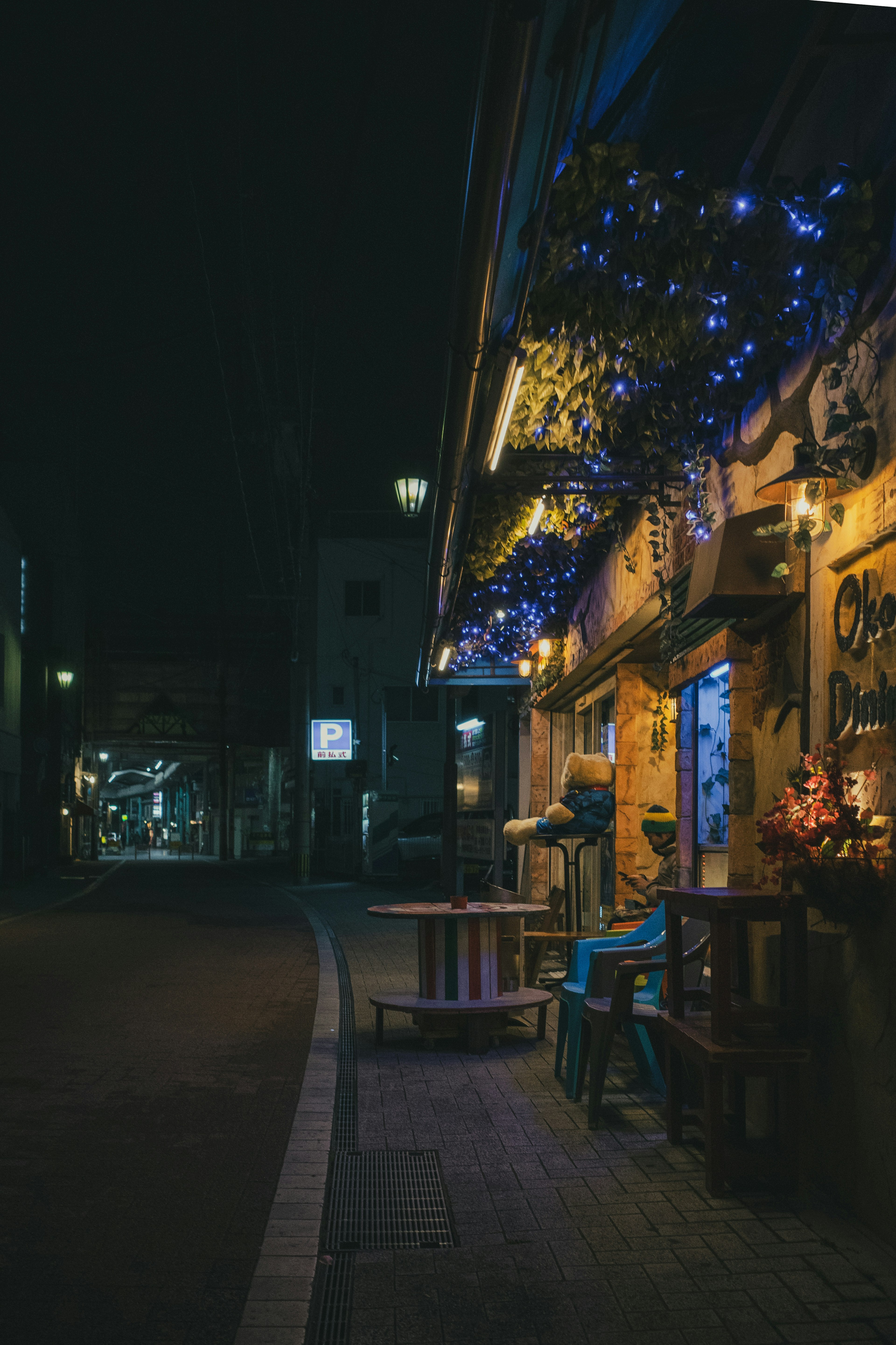 Vue nocturne d'un café avec des lumières bleues tables et chaises en bois