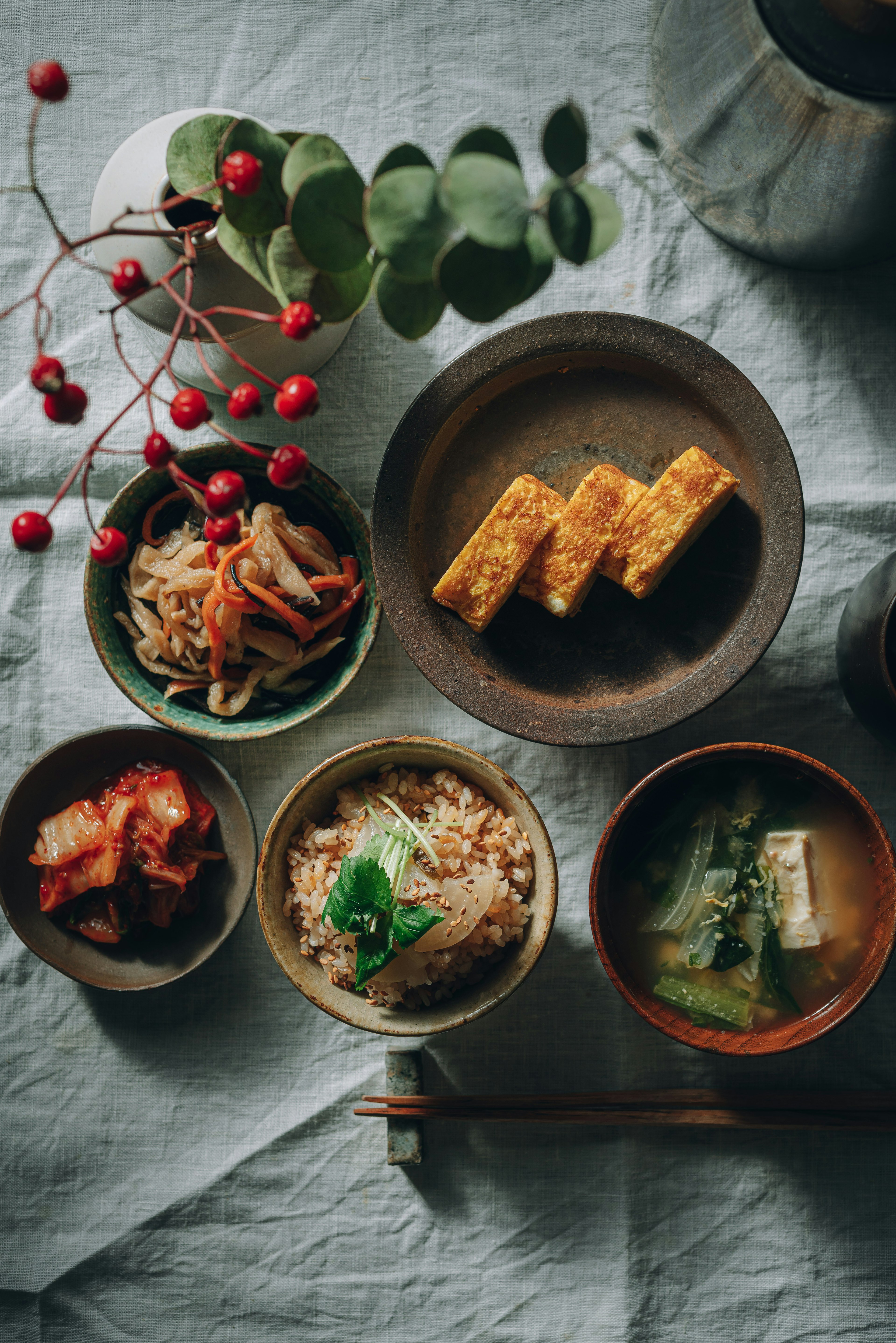 一頓餐點，桌上擺放著各種菜餚和紅色漿果的枝條