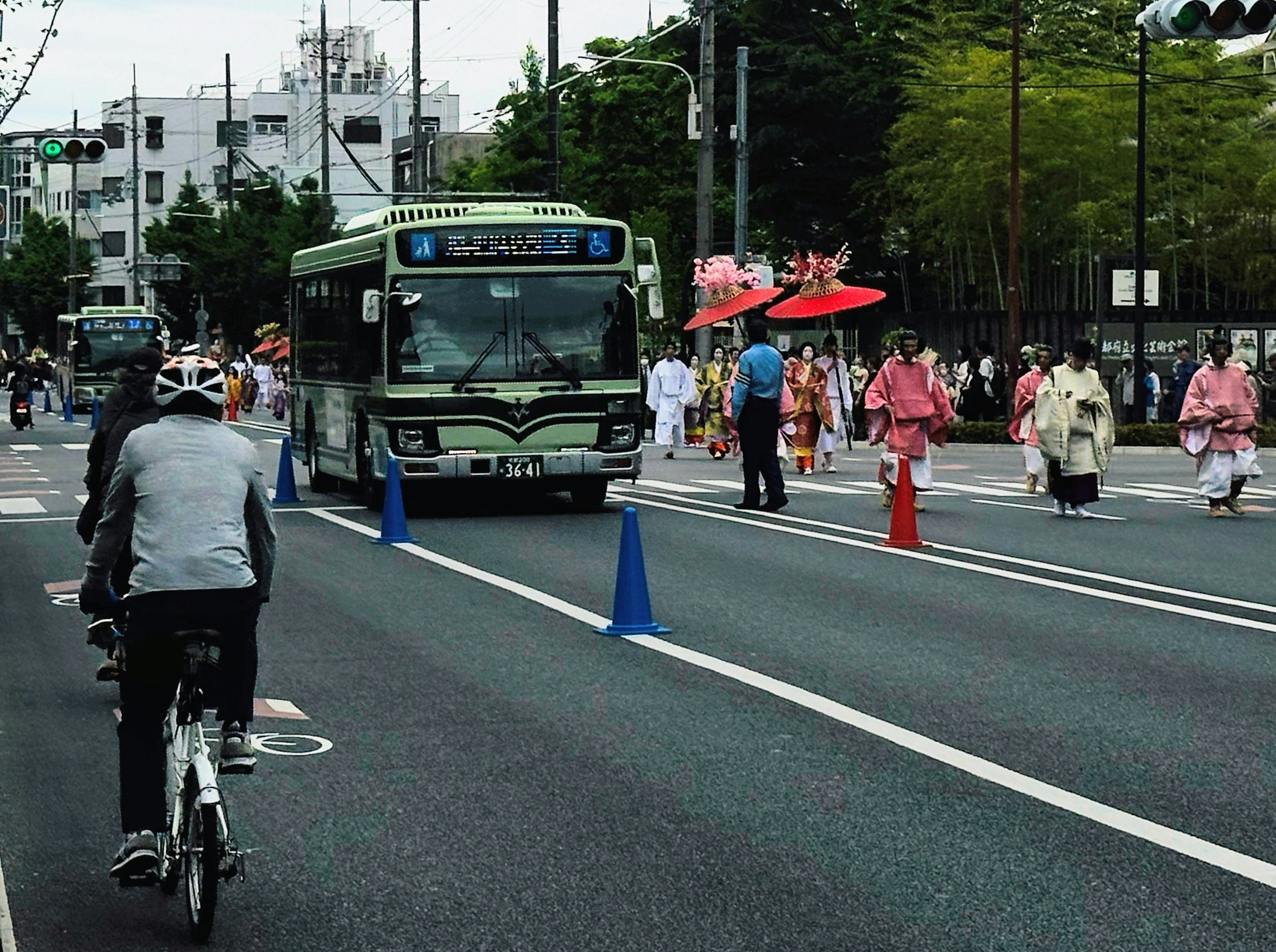 Scena cittadina in Giappone con un autobus e ciclisti e persone in abiti tradizionali in parata