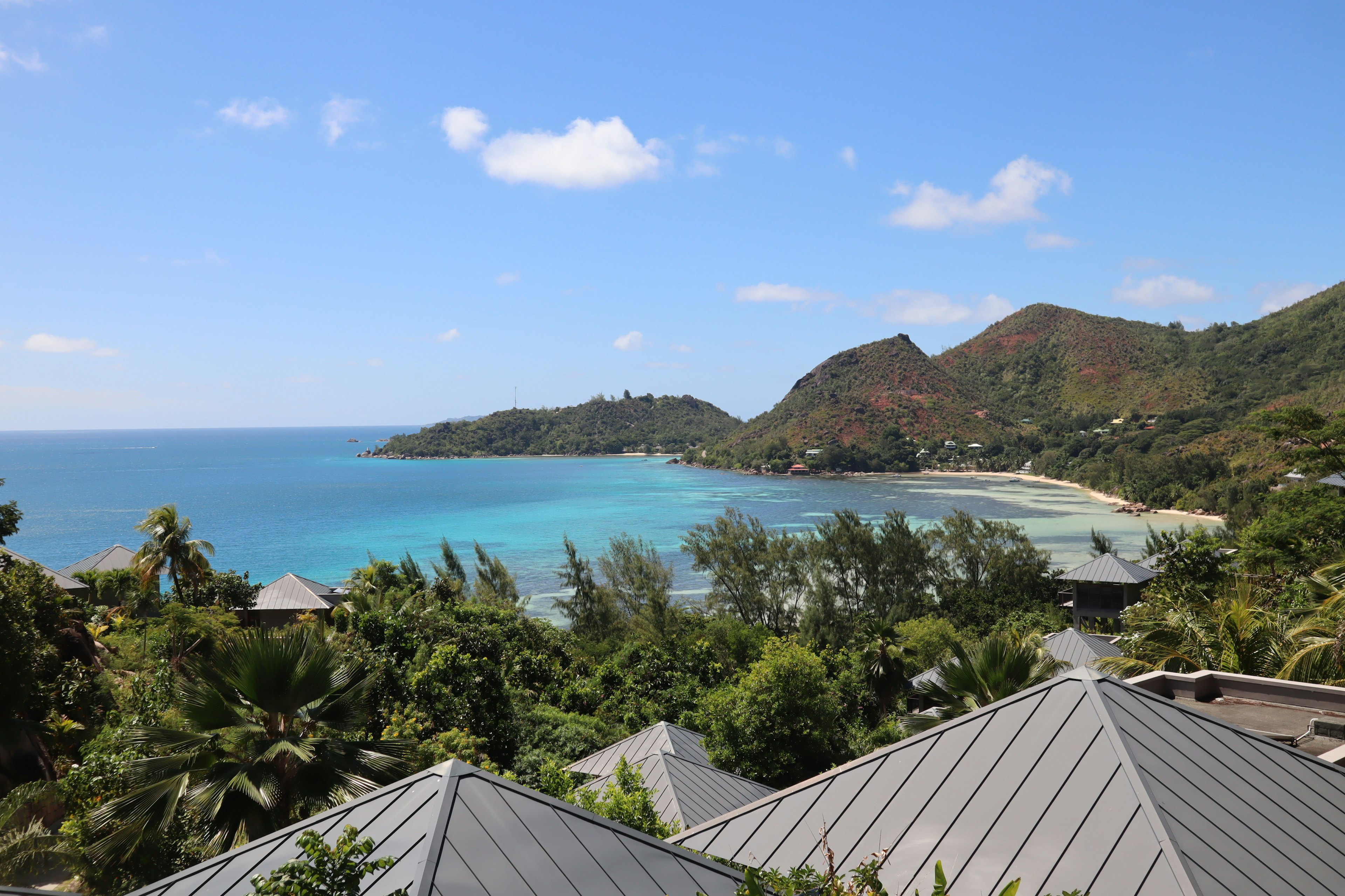 Scenic view of a beach with turquoise water lush greenery and mountains in the background