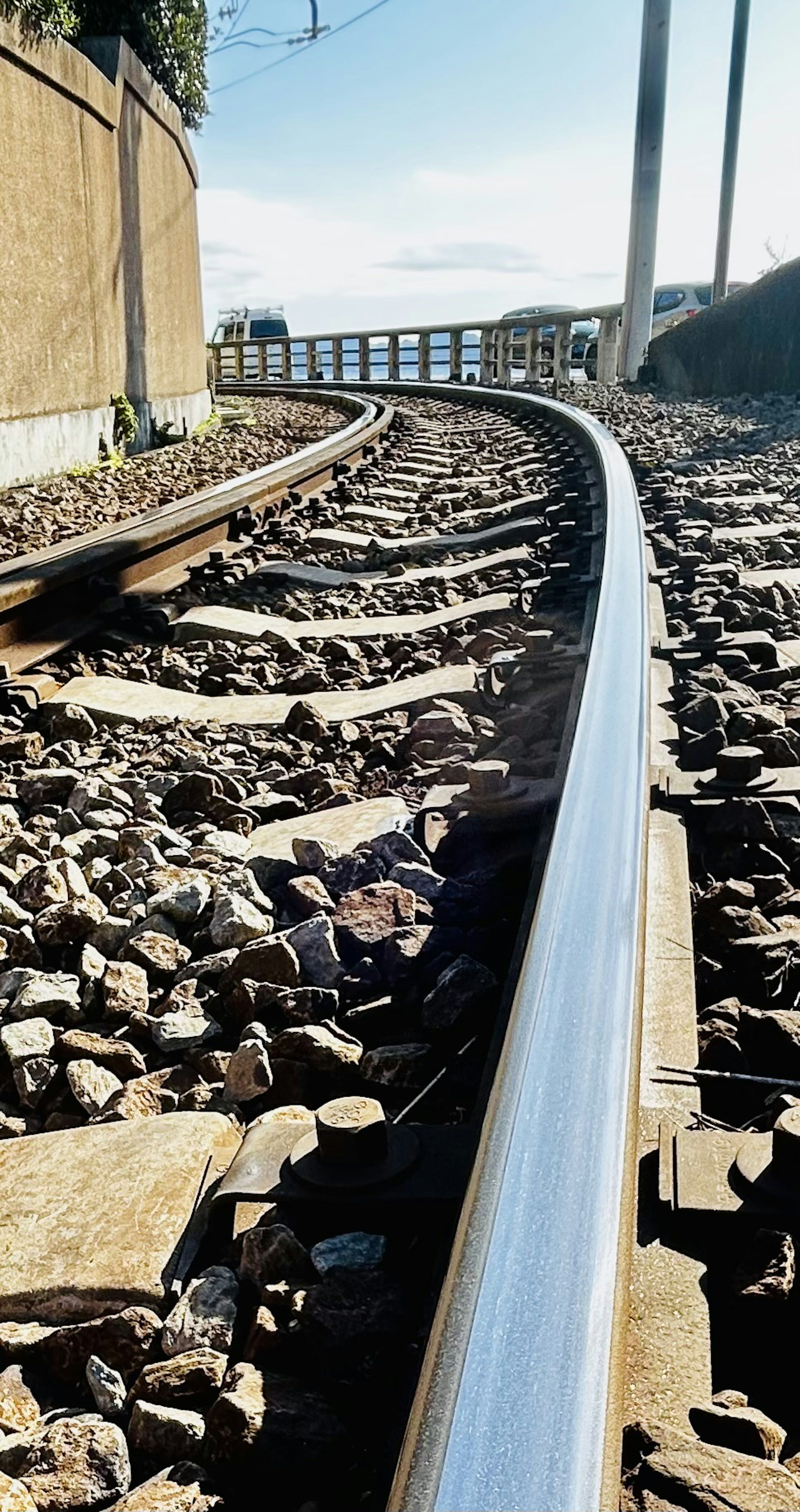 Curving railway track with gravel and a distant view