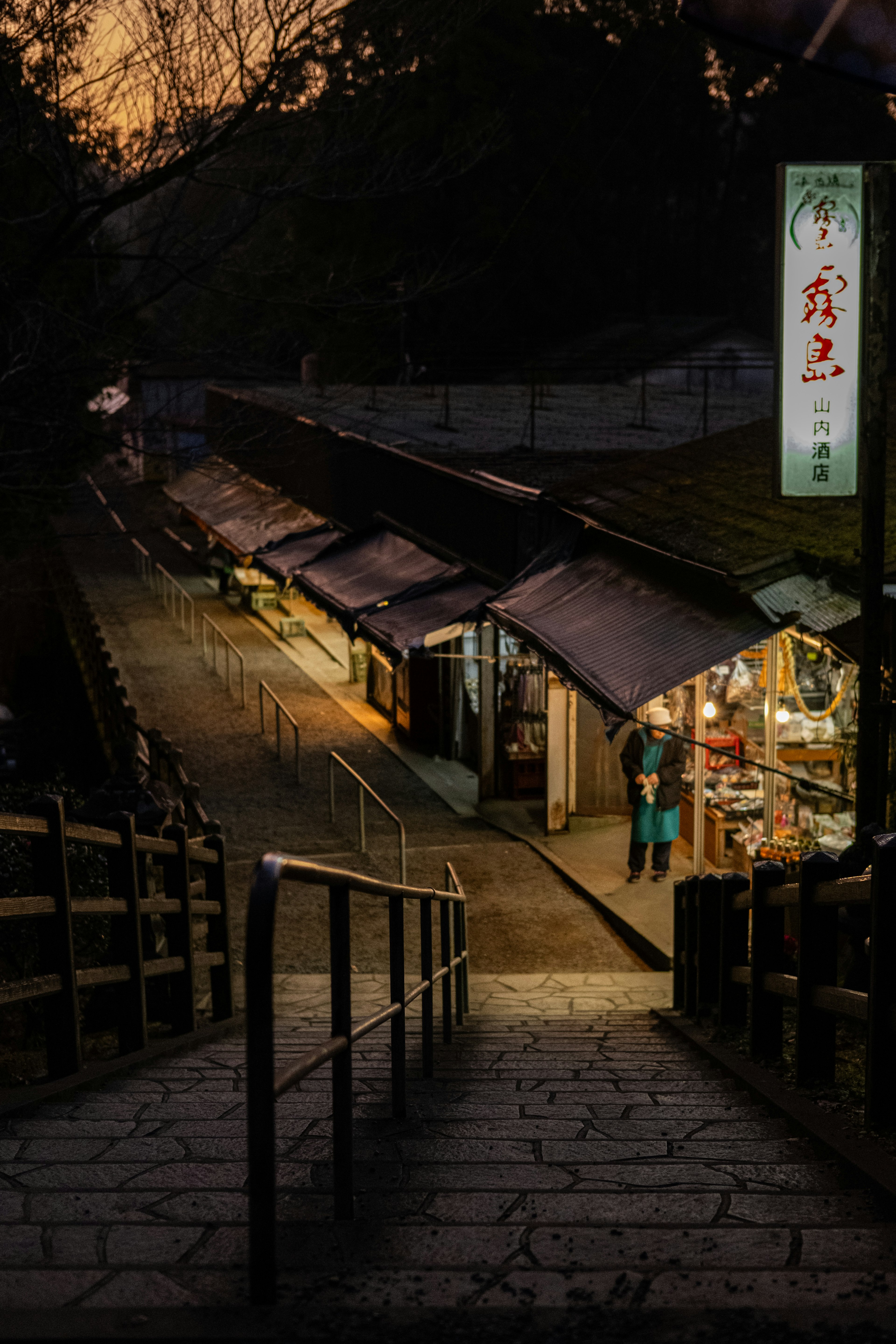 夕暮れ時の階段を下りていくと見える店が並ぶ風景