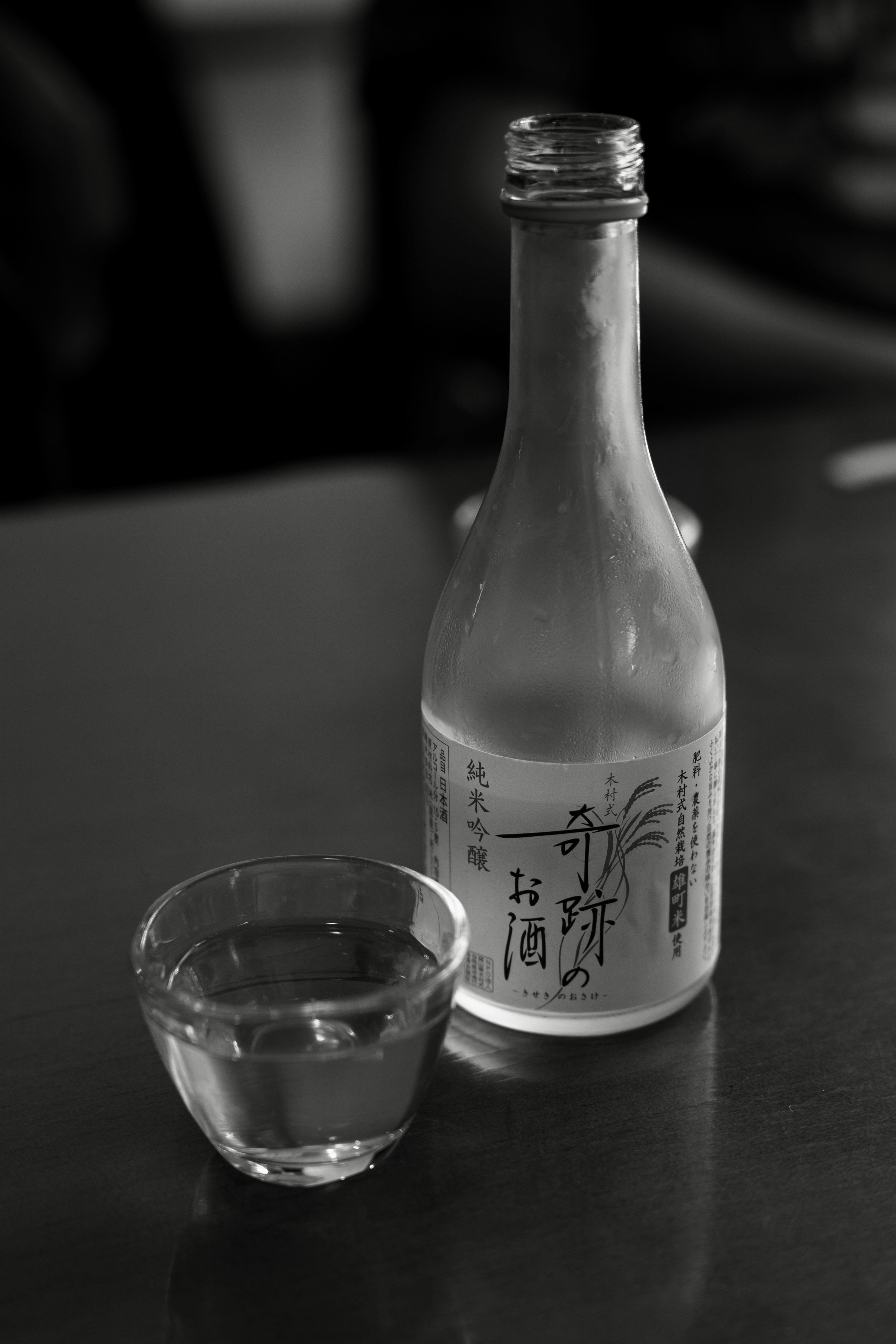 Una botella de sake y un pequeño vaso sobre un fondo oscuro