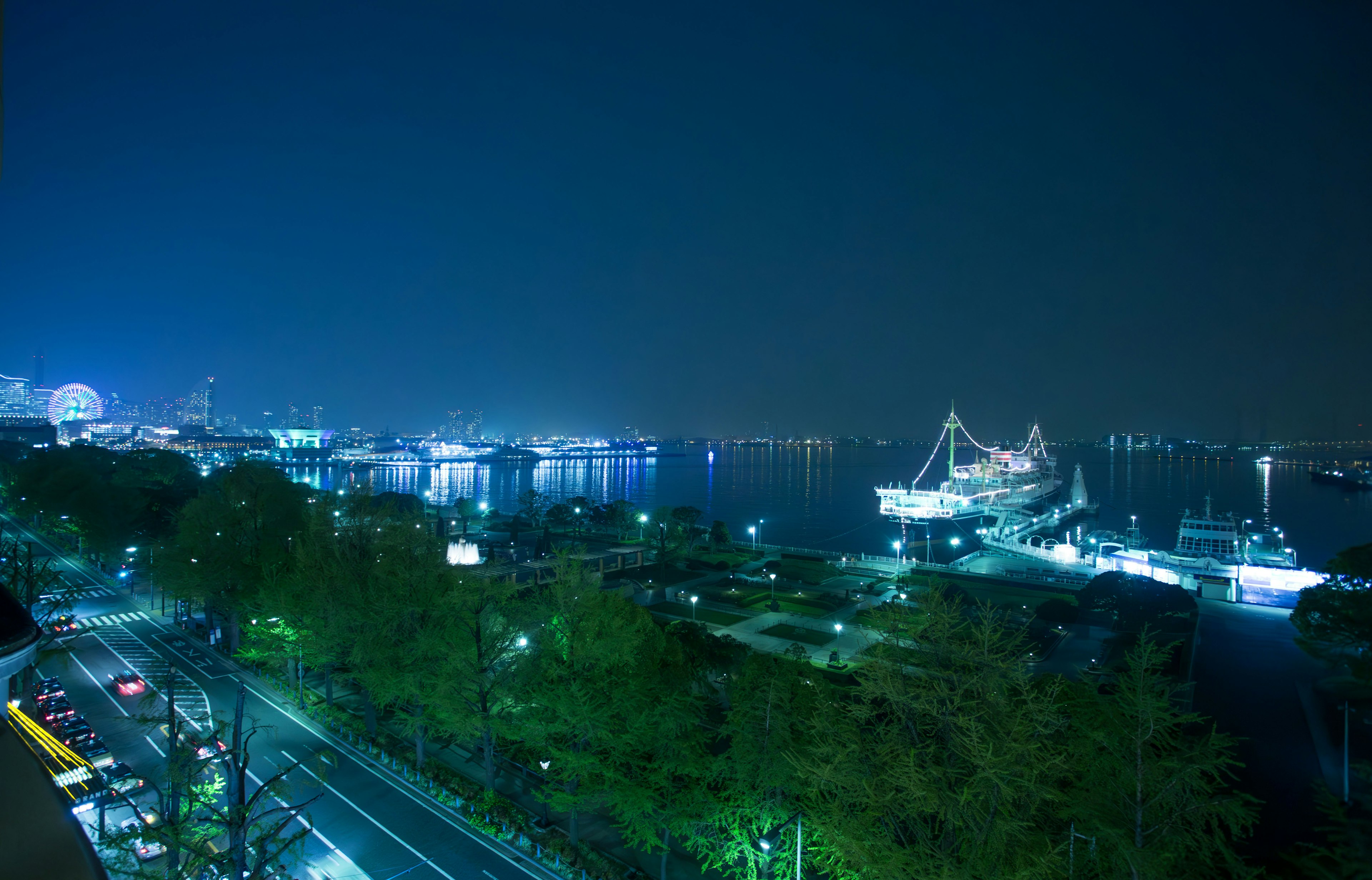 Vista nocturna de un puerto con barcos y luces de la ciudad