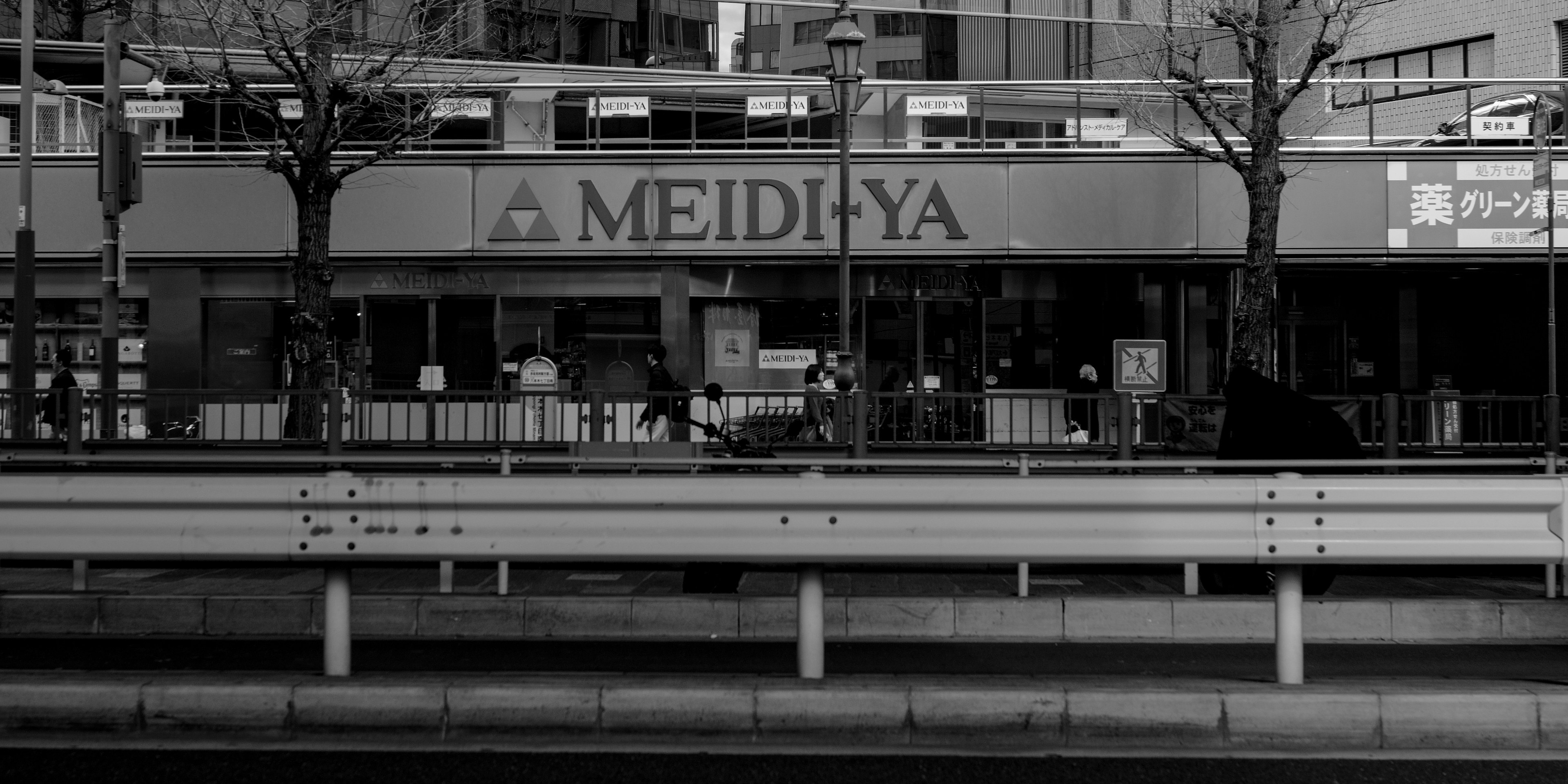 Vista en blanco y negro de la tienda Meidi-Ya en un entorno urbano