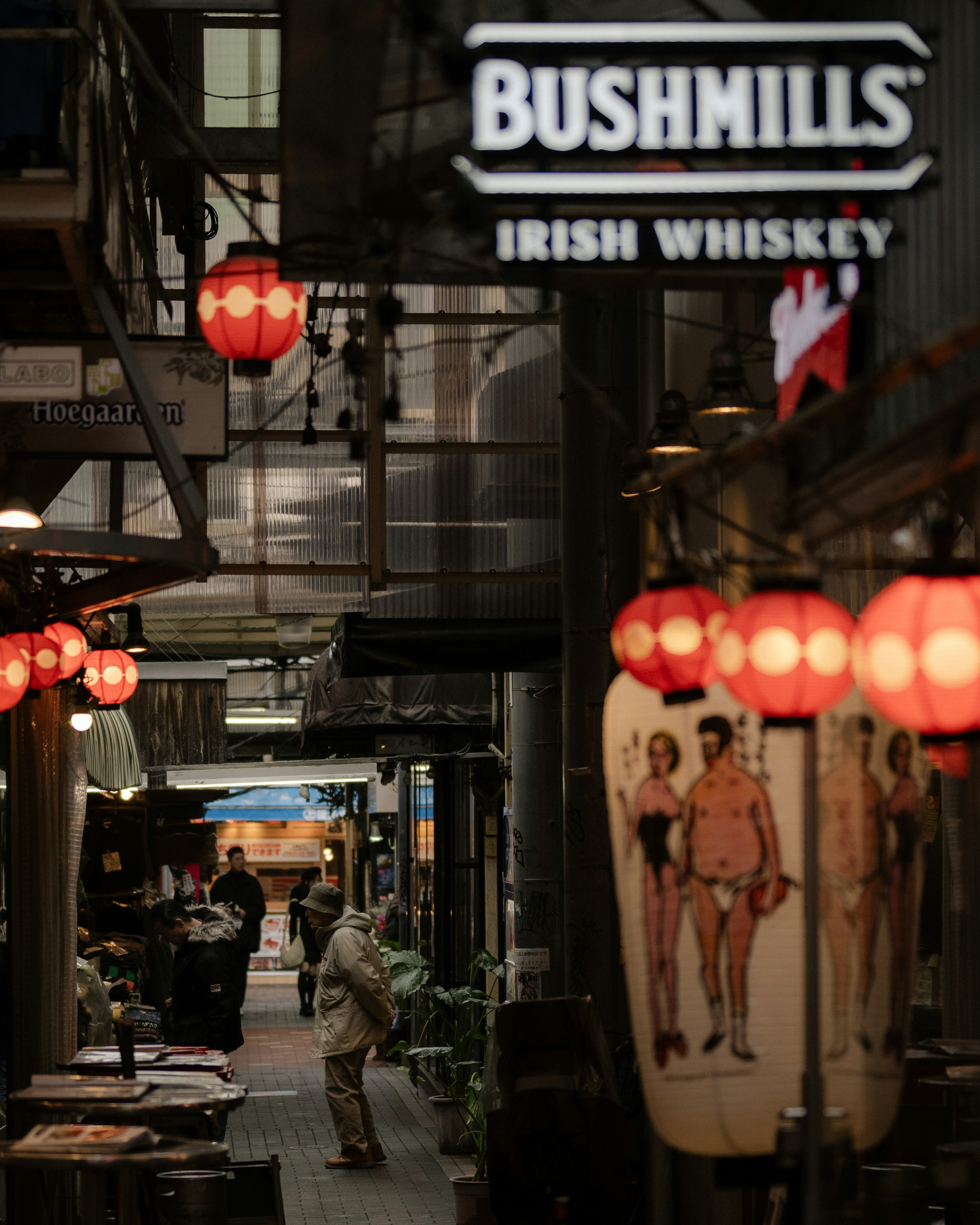 Callejón estrecho iluminado por farolillos con un cartel de Bushmills Irish Whiskey