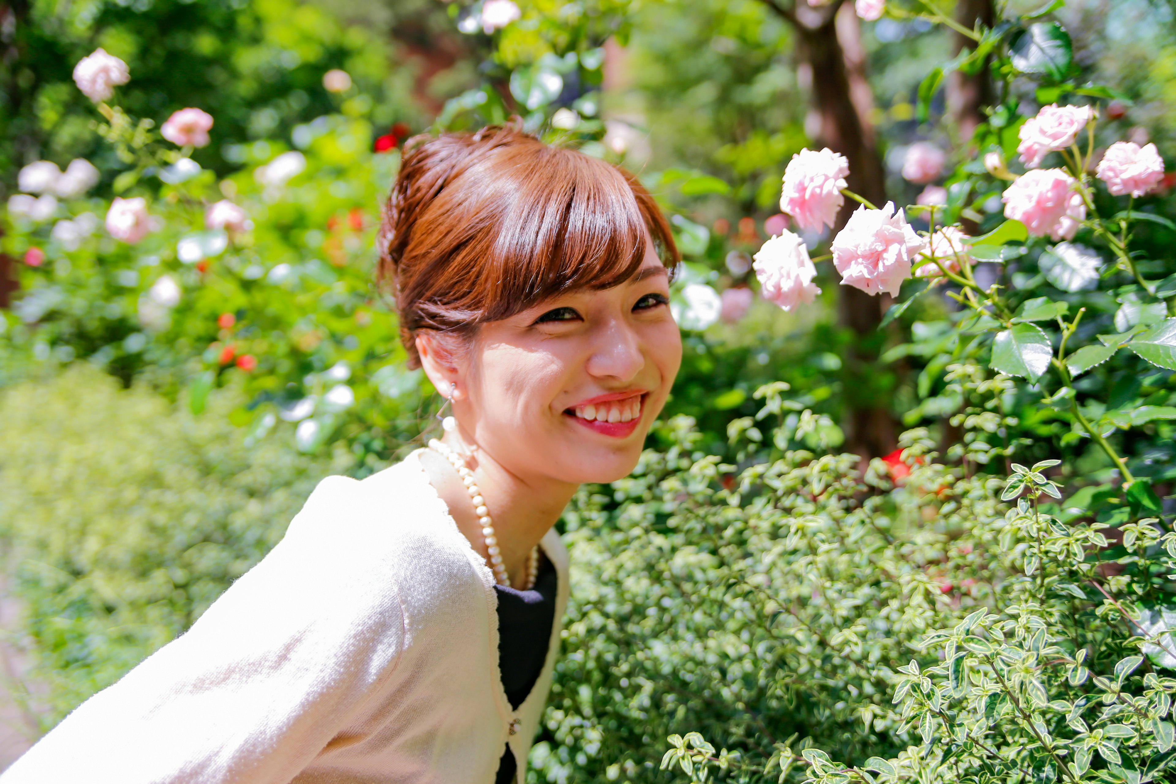 Ritratto di una donna sorridente davanti a rose in un parco