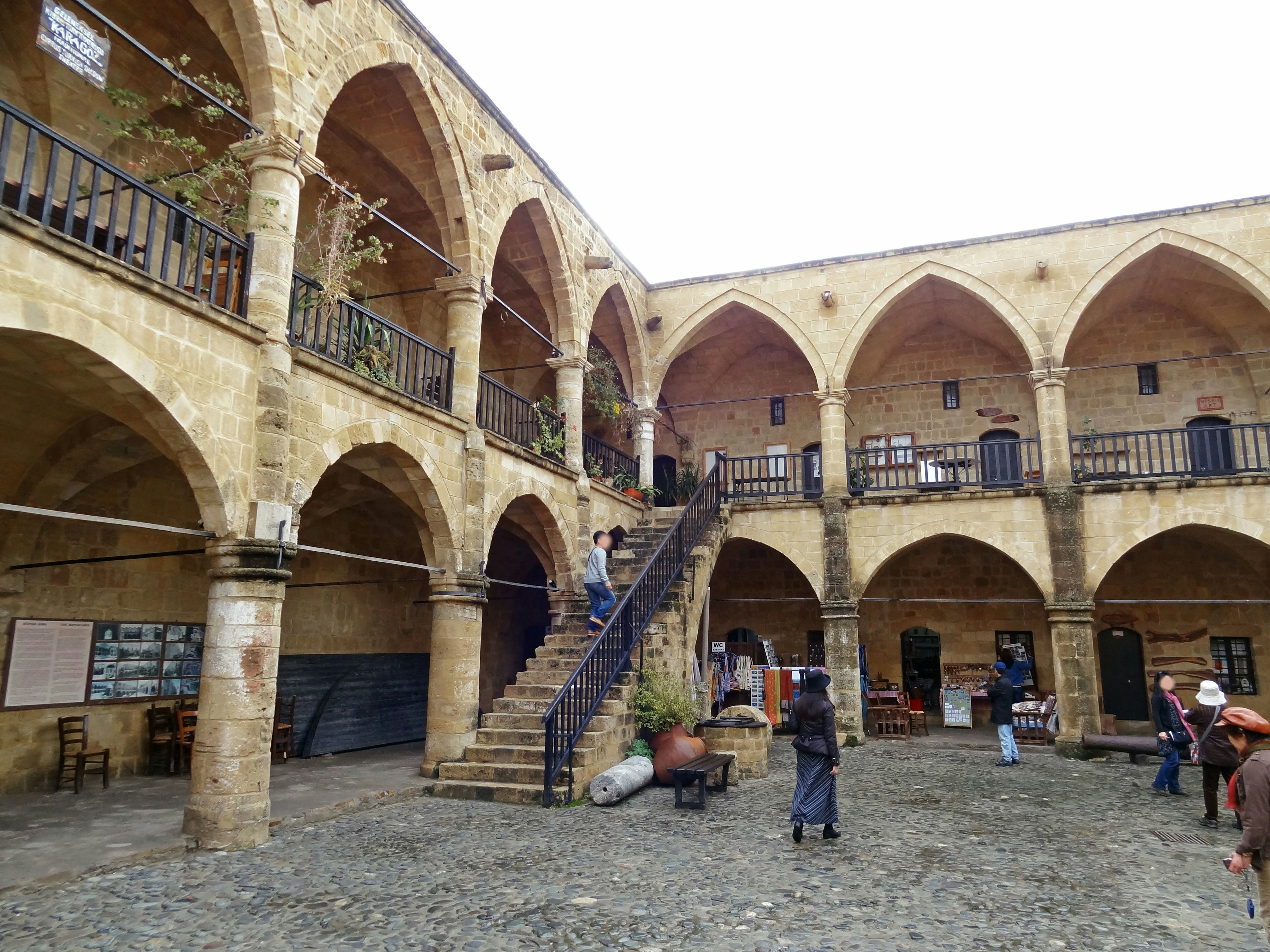 Cour intérieure d'un bâtiment historique avec des colonnes arquées et un escalier