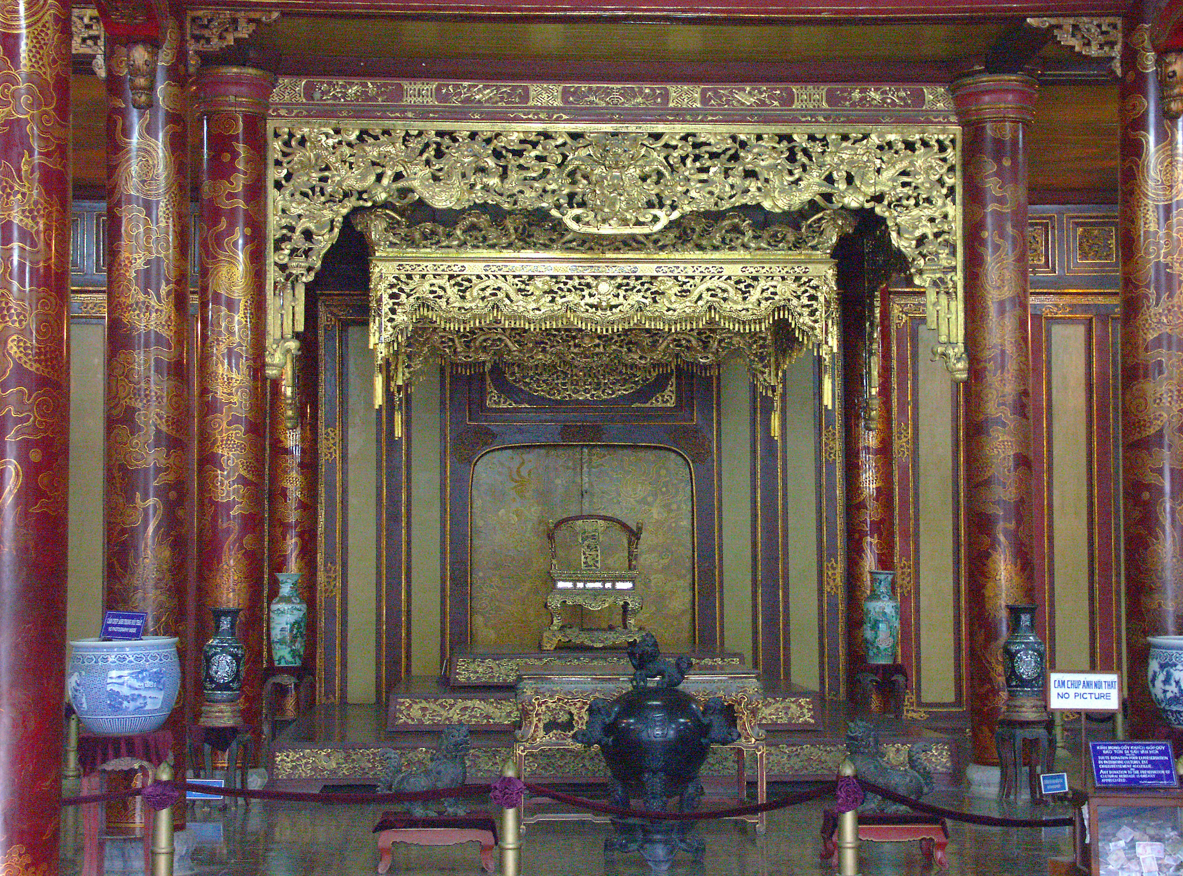 Interior de una habitación tradicional con decoraciones doradas ornamentadas y columnas de madera