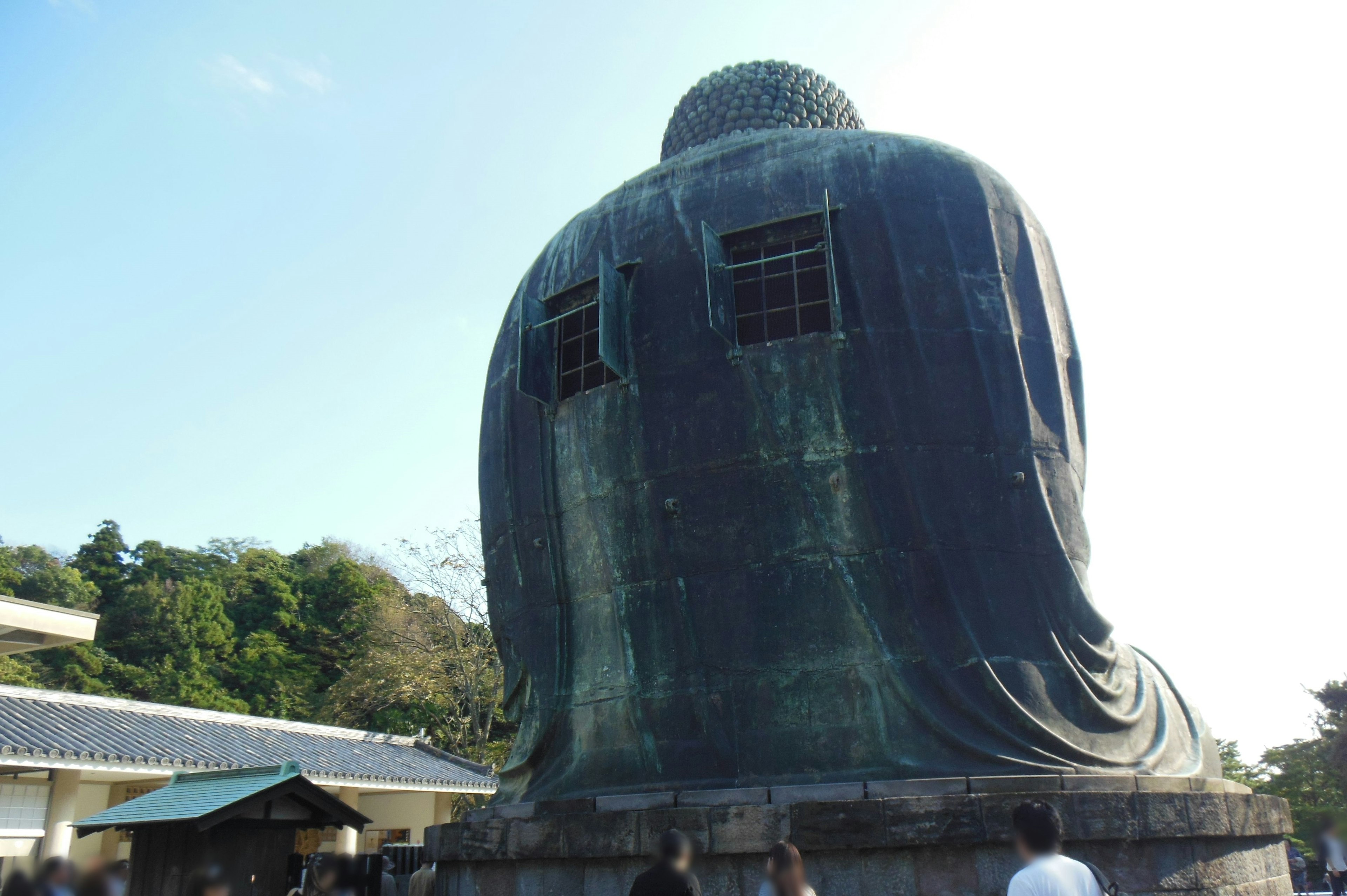 Gambar patung Buddha besar dilihat dari belakang dengan orang-orang di sekitarnya